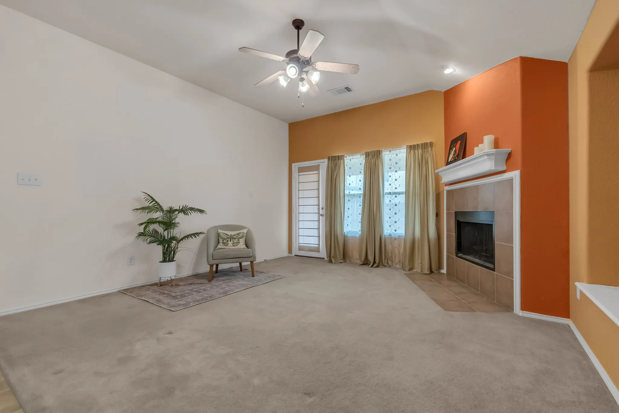 Vaulted ceiling with a ceiling fan, fireplace with a tile surround and mantle, and a built-in window seat