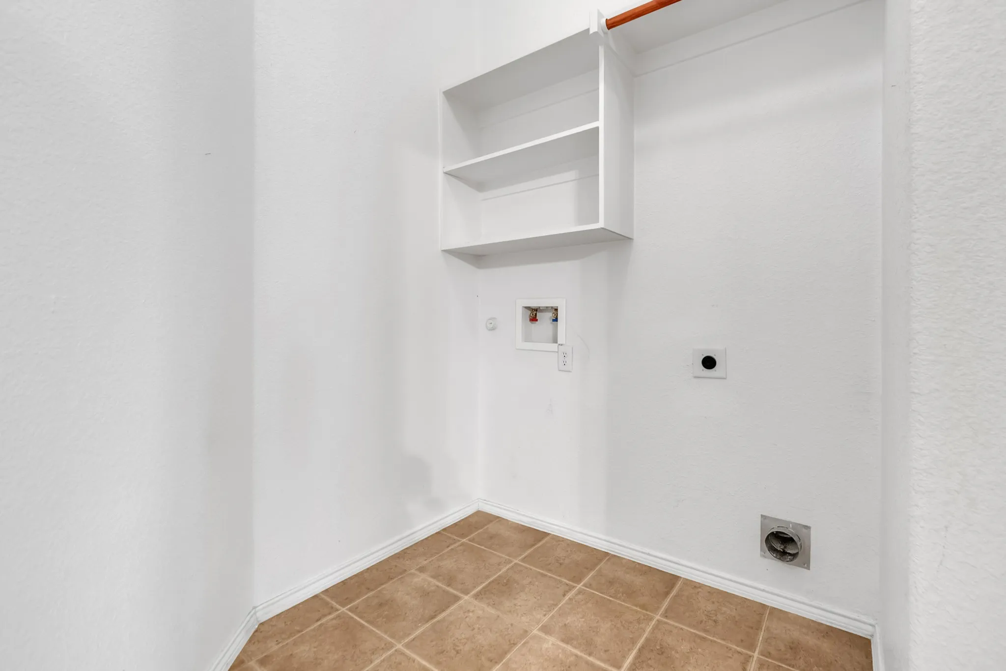 White walls with built-in shelving, a clothes hanging rod, and tile flooring