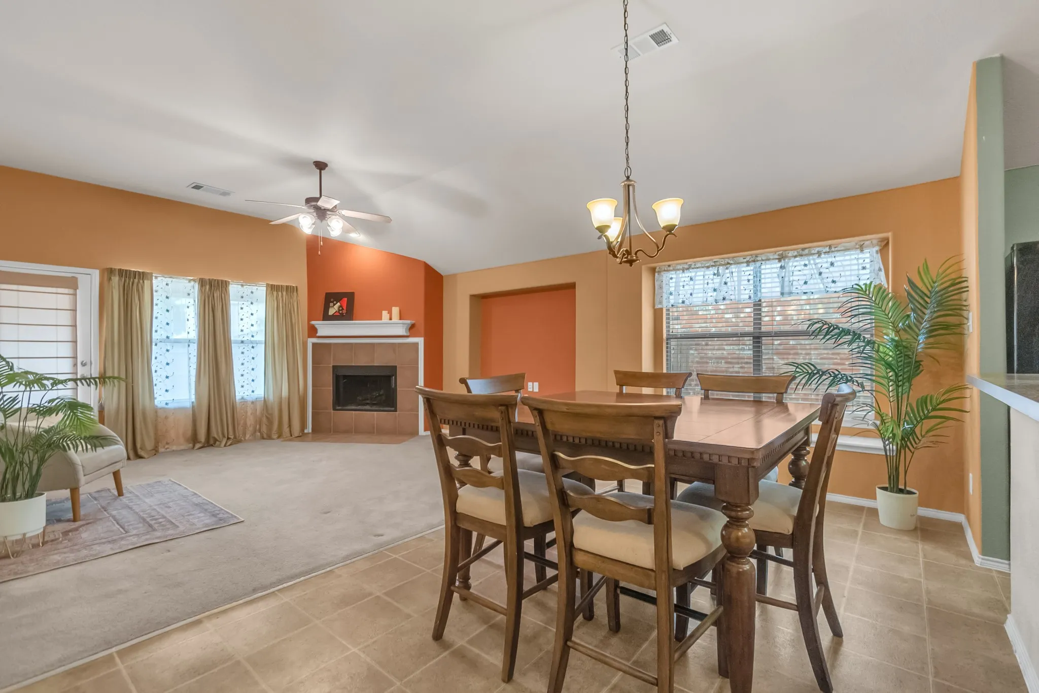 Vaulted ceiling, ceiling fan, fireplace with mantel, tiled flooring, and a chandelier
