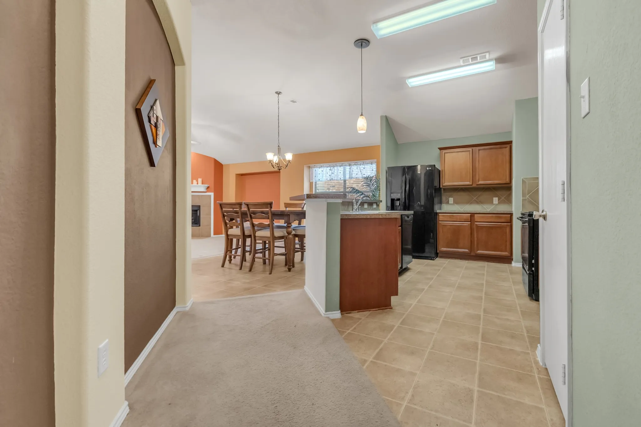 Kitchen featuring tile flooring, wooden cabinetry, and black appliances