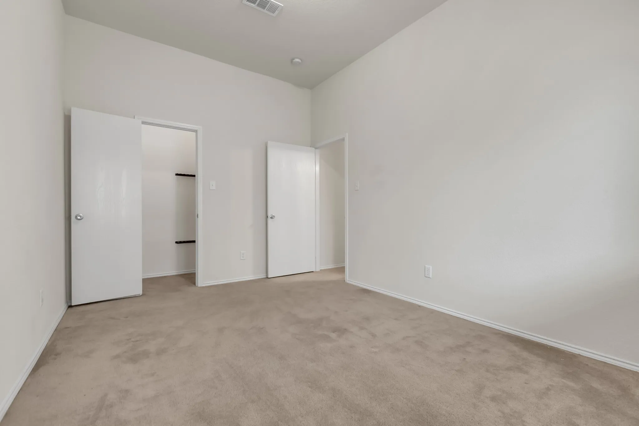 Carpeted flooring, vaulted ceiling, white walls, and two interior doors