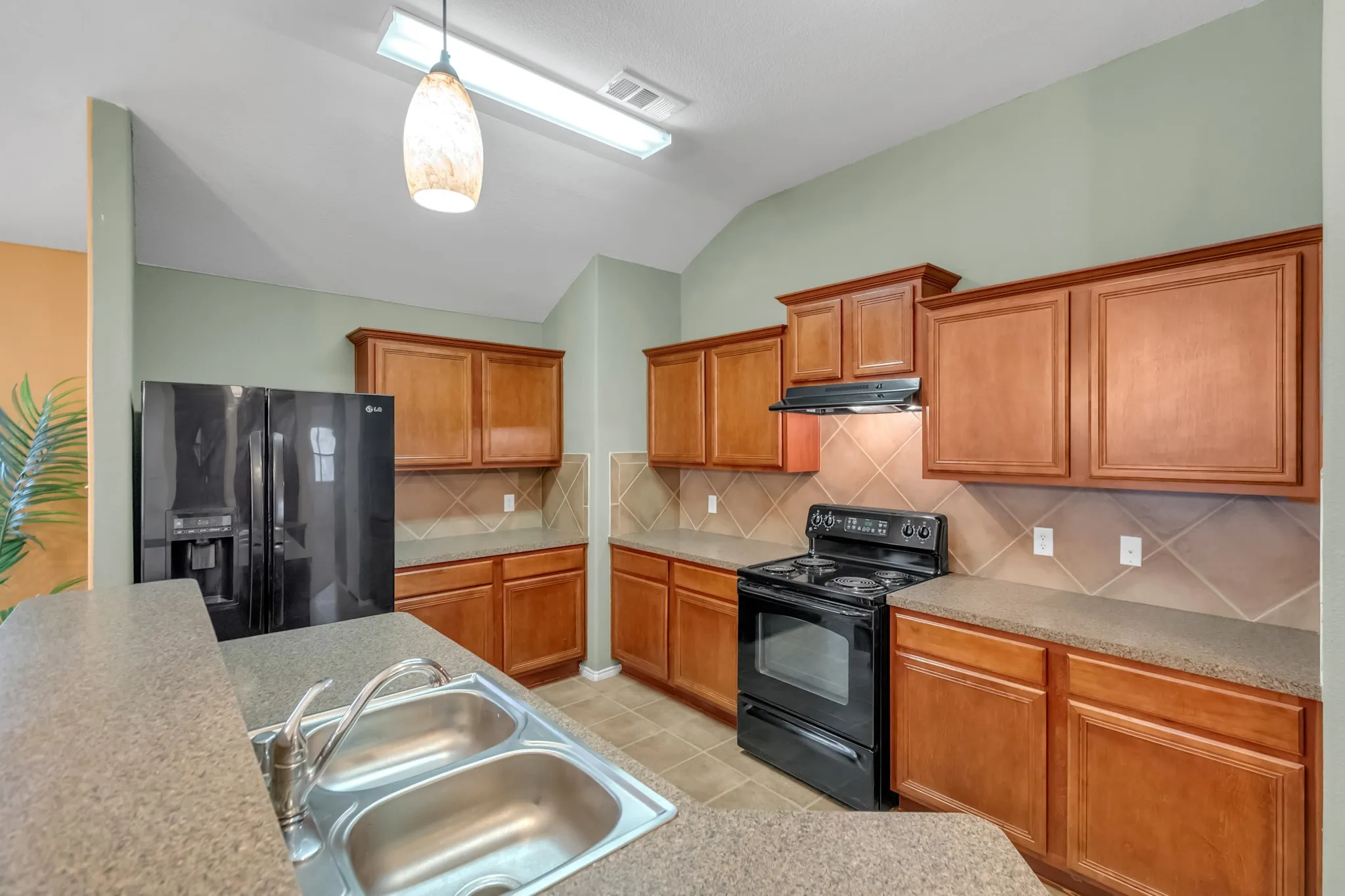 Kitchen featuring wood cabinetry, a double basin stainless steel sink, tile flooring, and a tiled backsplash