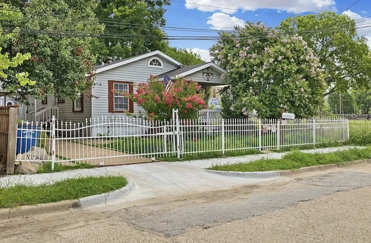 Siding exterior featuring a front porch, white picket fencing, and mature landscaping