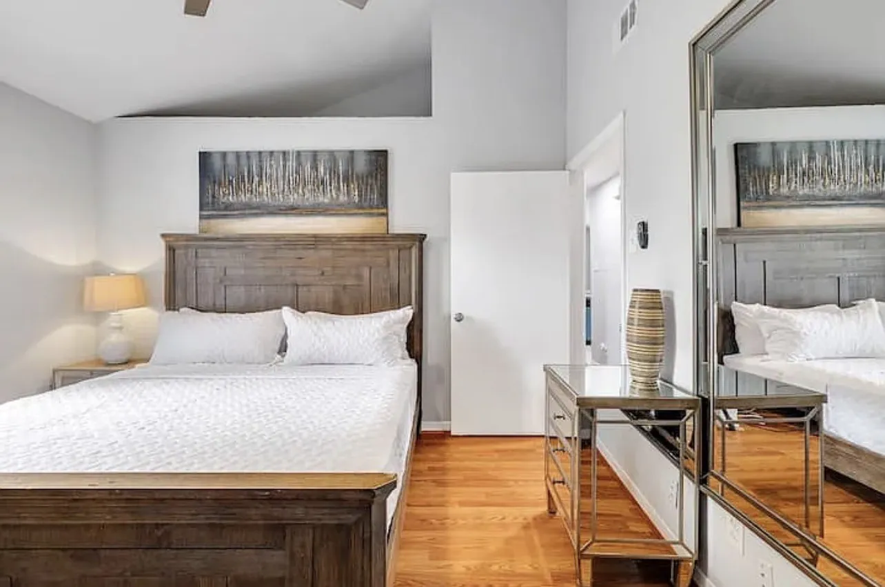 Vaulted ceiling with a ceiling fan, wood-finish flooring, and a mirrored closet door