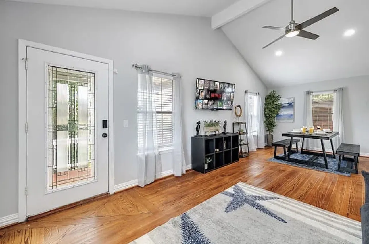 Vaulted ceiling with a contemporary ceiling fan, wood-finish flooring, and a white entry door with decorative glass paneling