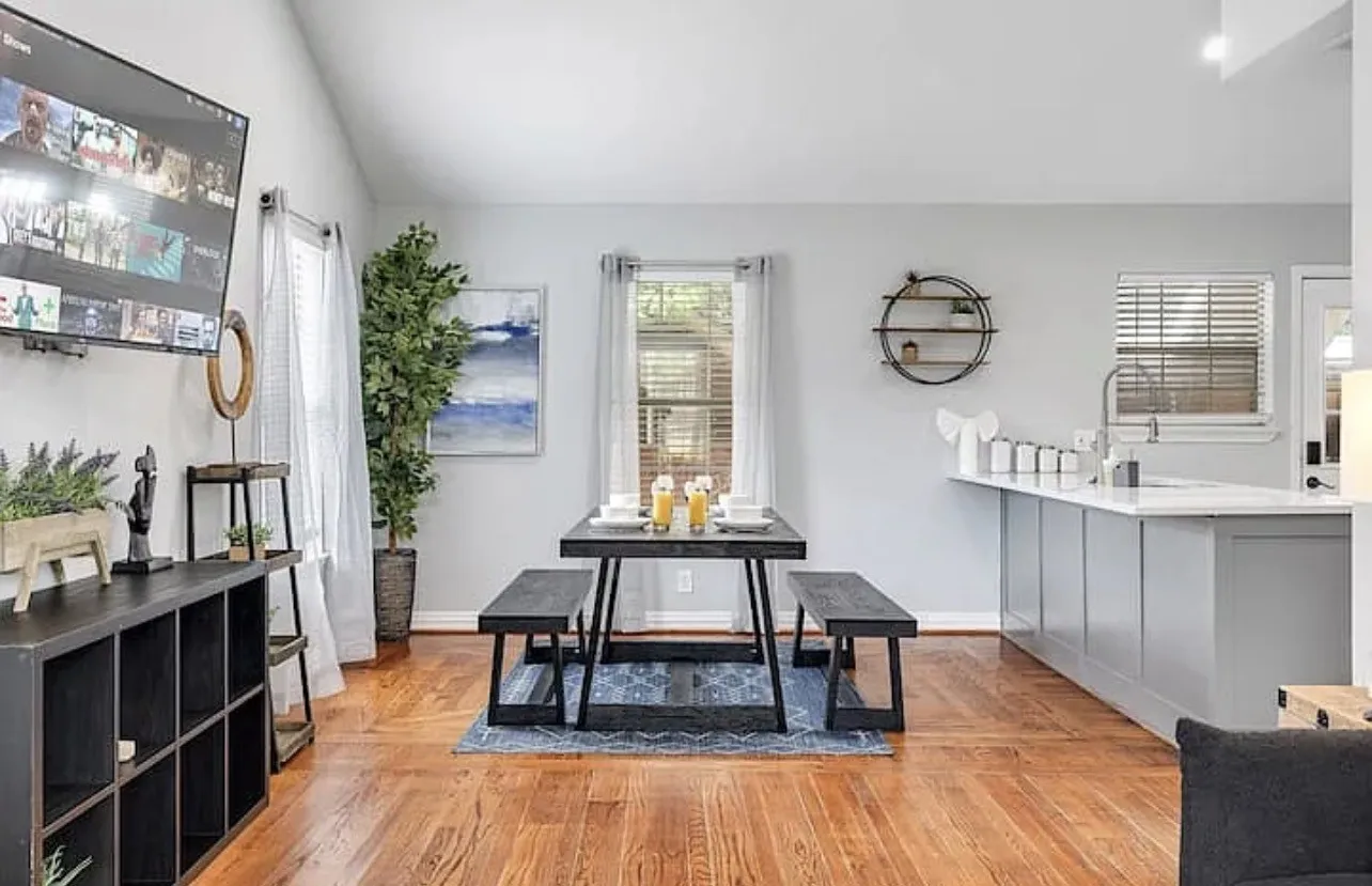Vaulted ceiling, wood-finish flooring, light grey walls, kitchen island with sink, and built-in shelving