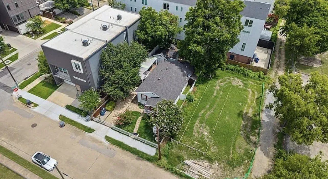 Residential property featuring an expansive grass lot, a paved driveway, and mature trees