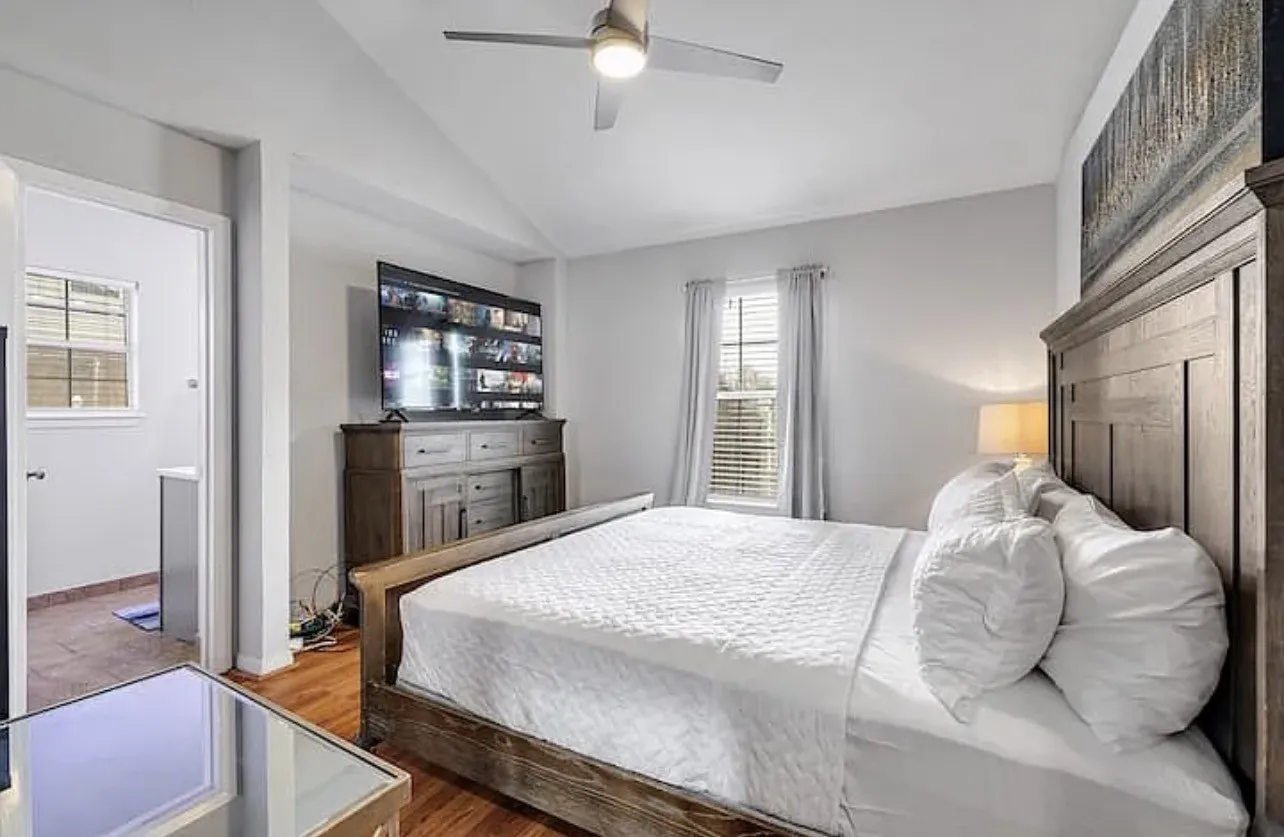 Vaulted ceiling, wood-finish flooring, ceiling fan, natural light from window, and attached bathroom