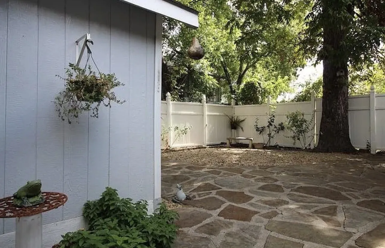 Flagstone patio with a white privacy fence and mature trees