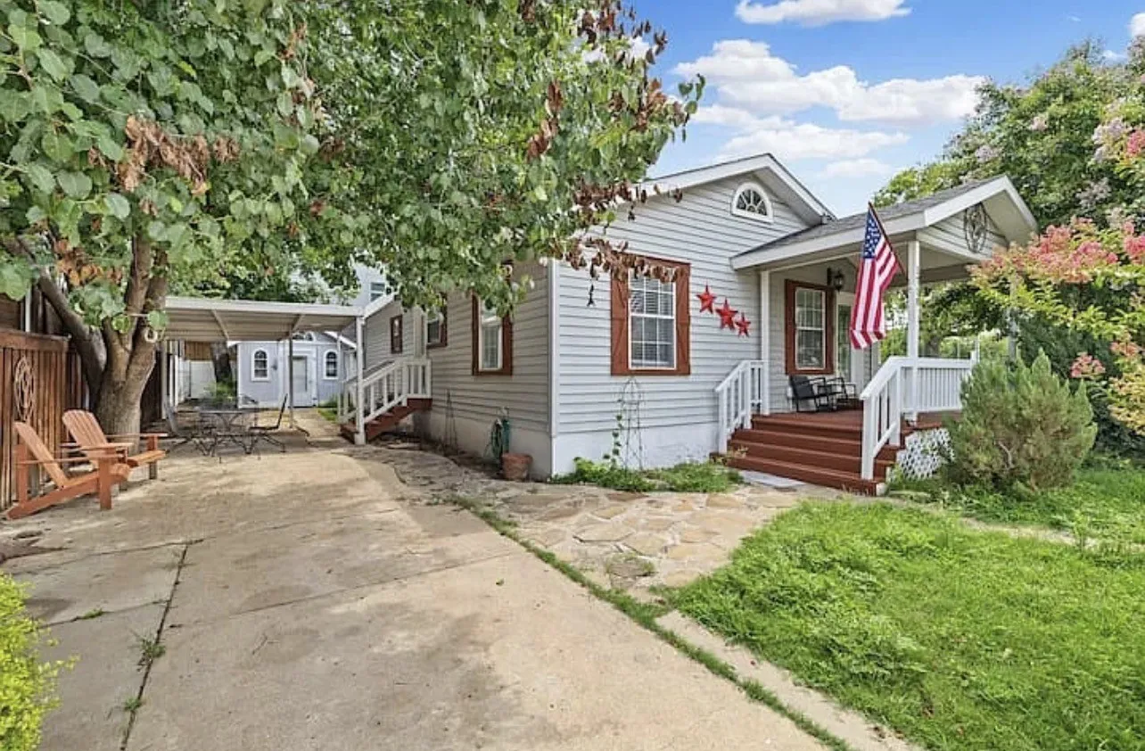 Siding exterior with dormer detail, covered front porch, and wood-finish steps
