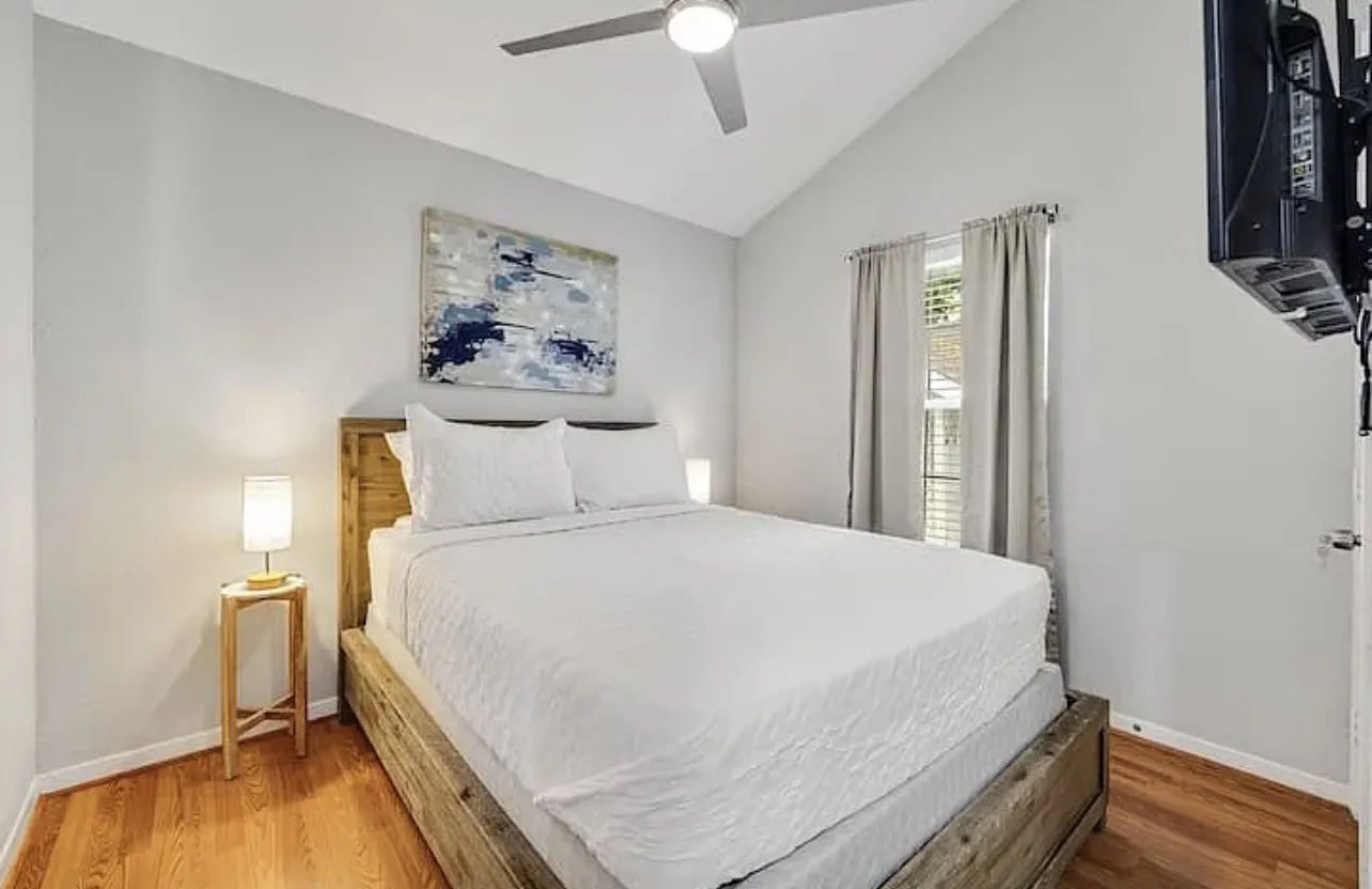 Vaulted ceiling with a ceiling fan, hardwood flooring, and neutral wall tones