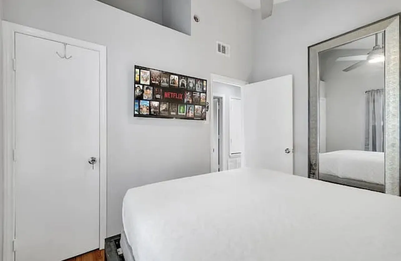 Vaulted ceiling, ceiling fan, hard-surface flooring, large framed mirror, recessed wall opening