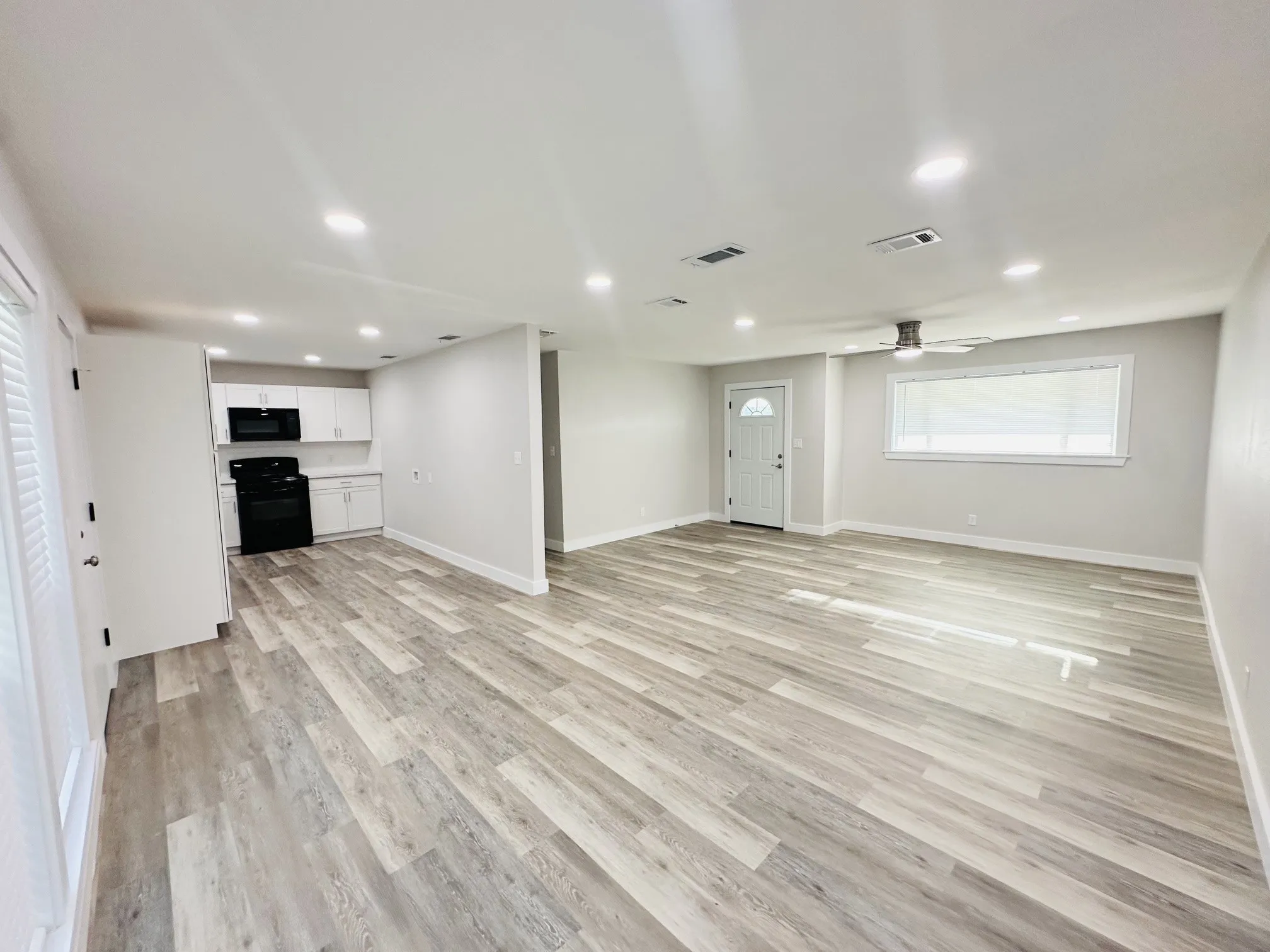 Open-concept living space with wood-finish flooring, recessed lighting, and a ceiling fan