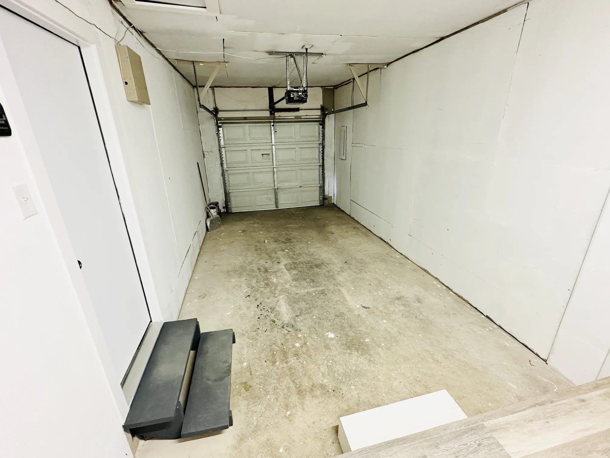 Garage space featuring a roll-up door, concrete flooring, and an interior access door