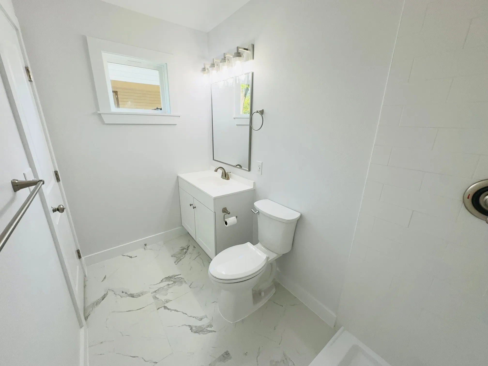 White vanity with integrated sink, rectangular mirror, light fixture, and patterned tile flooring