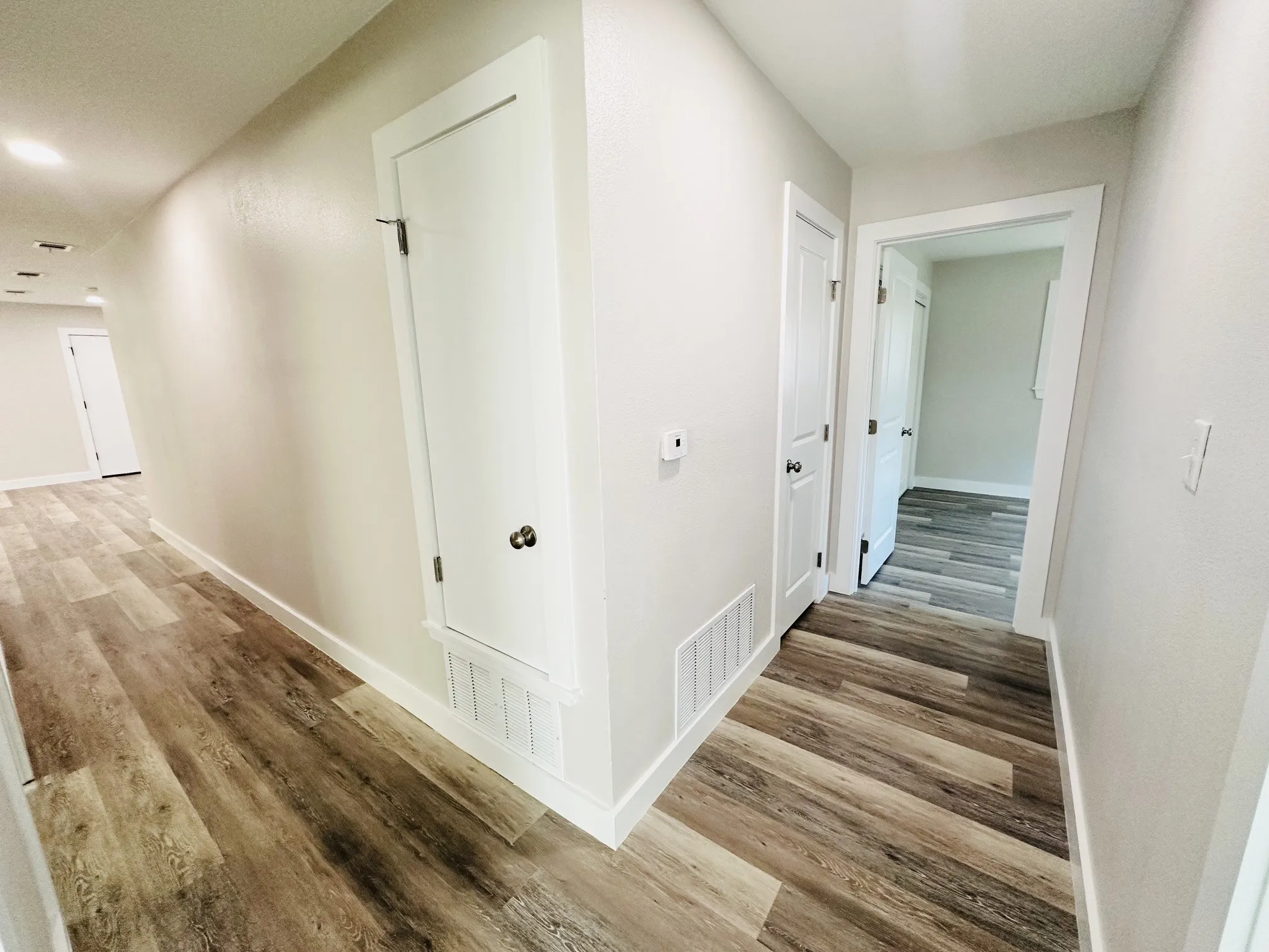 Wood-finish flooring throughout, white trim, and white doors