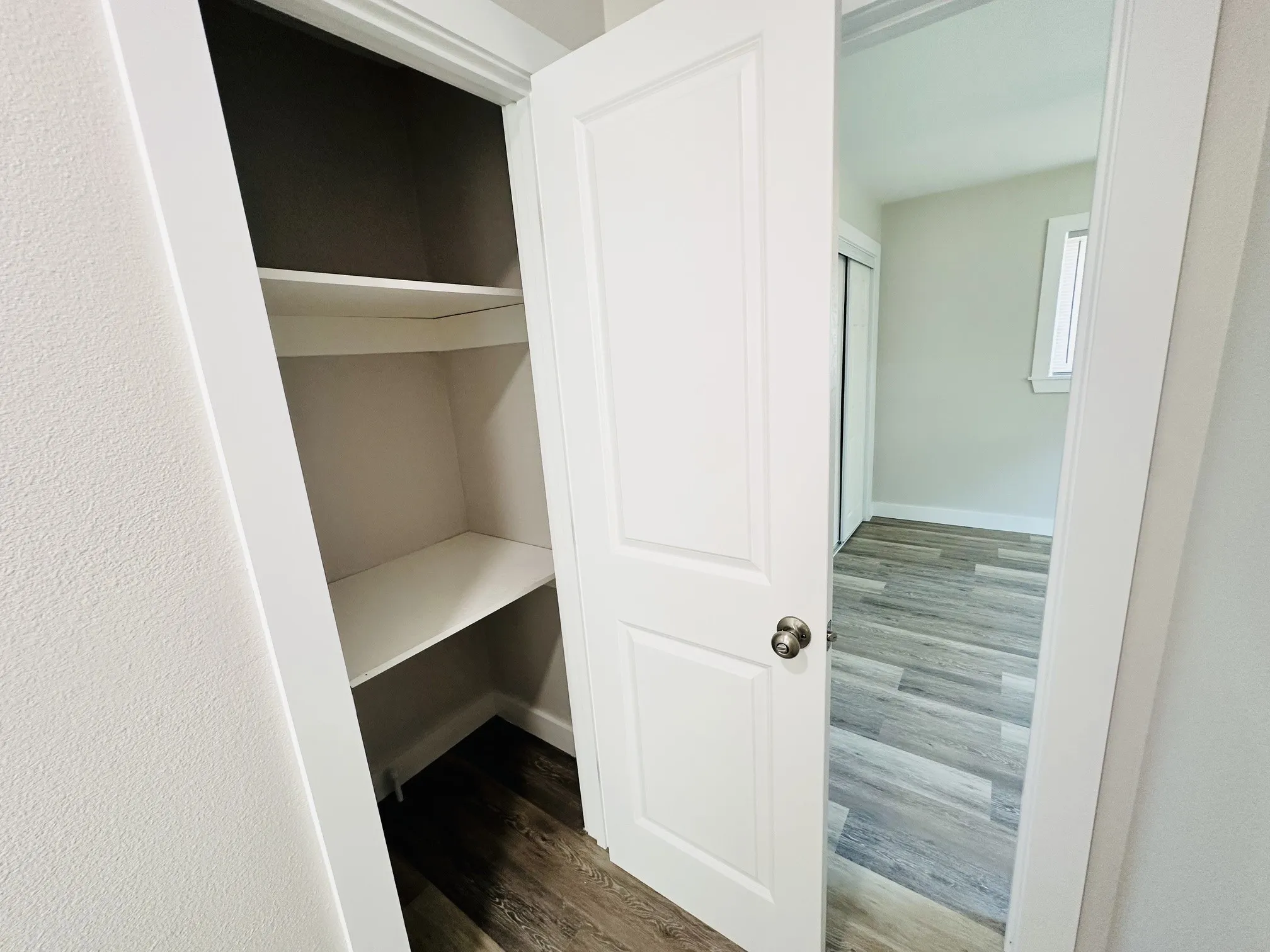 Built-in shelving, white paneled door, light-colored wood-finish flooring, white trim details, sliding closet doors