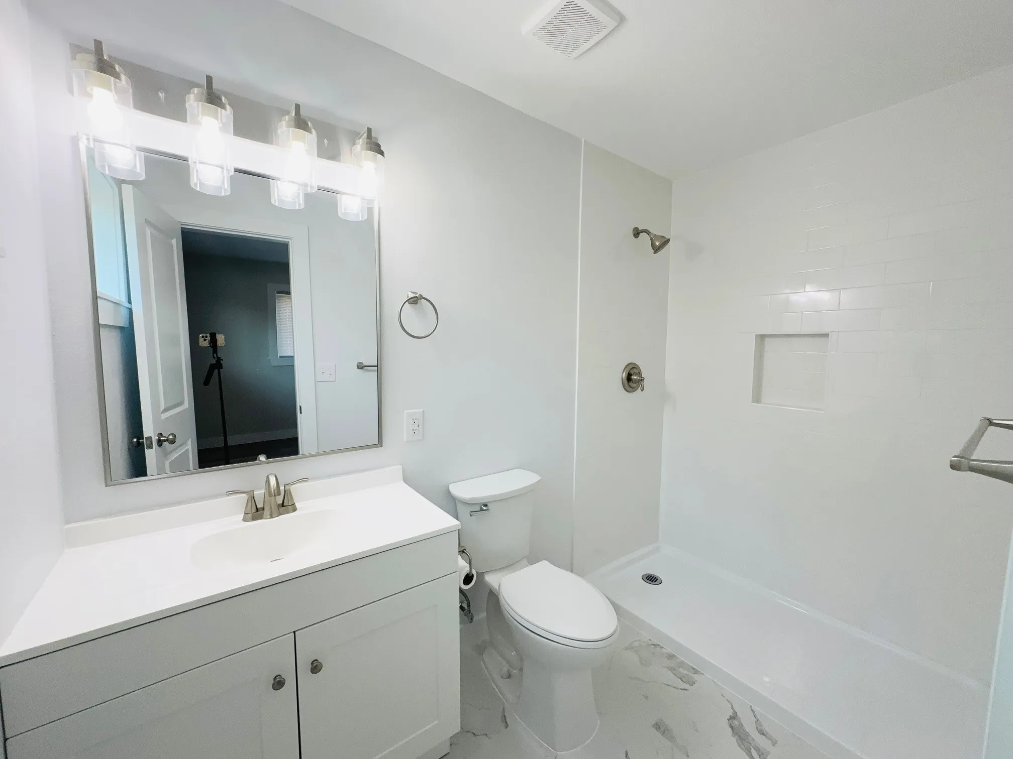 Modern bathroom with a walk-in shower, white subway tile surround, recessed shower niche, and a vanity with a white countertop