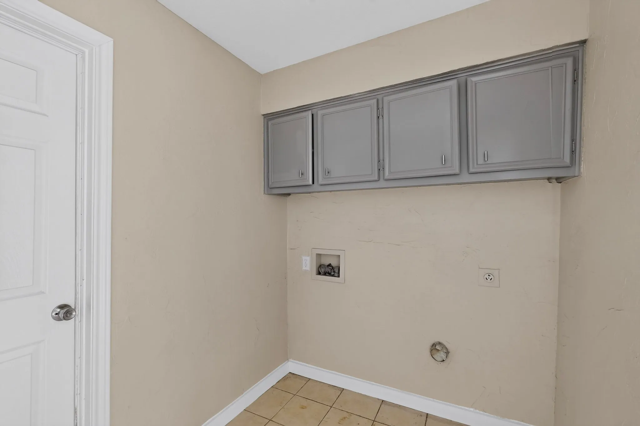 Laundry area featuring overhead cabinetry, neutral wall paint, and tile flooring