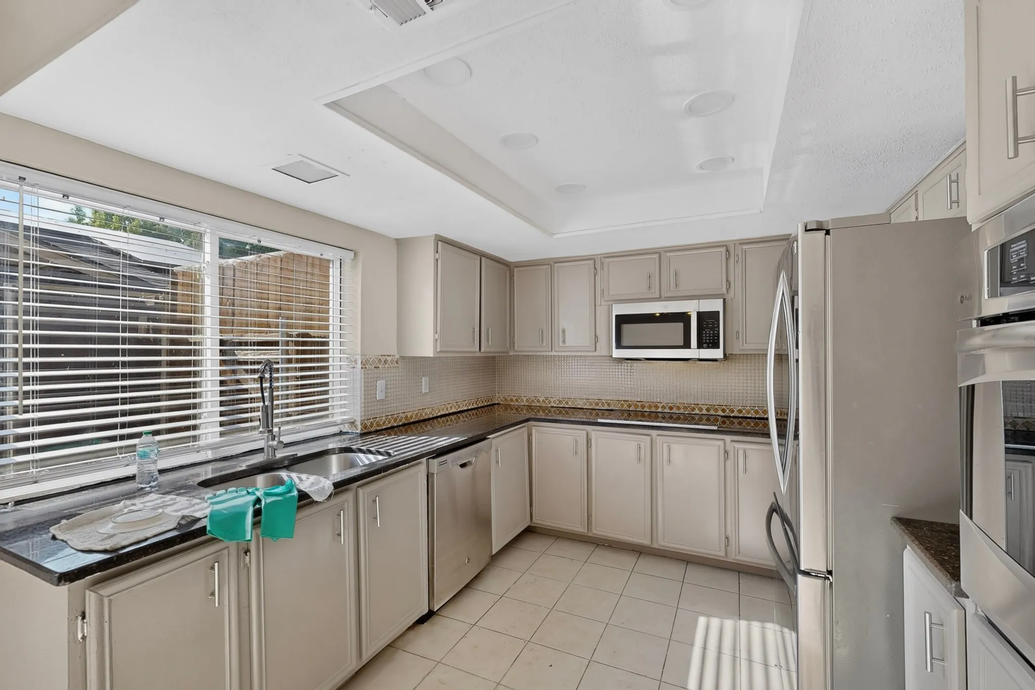 Kitchen featuring white cabinetry, dark countertops, stainless steel appliances, and tile flooring