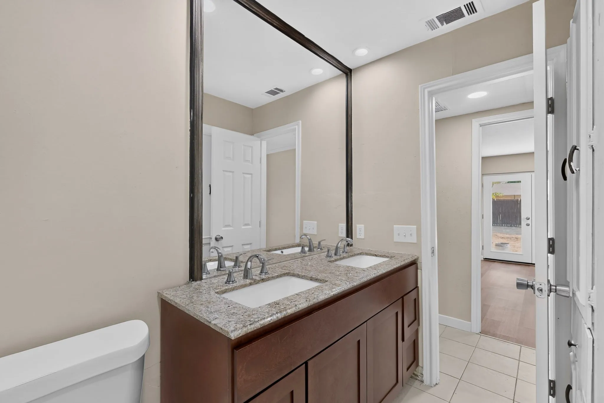 Double vanity with granite-style countertop, dual undermount sinks, and brushed nickel fixtures