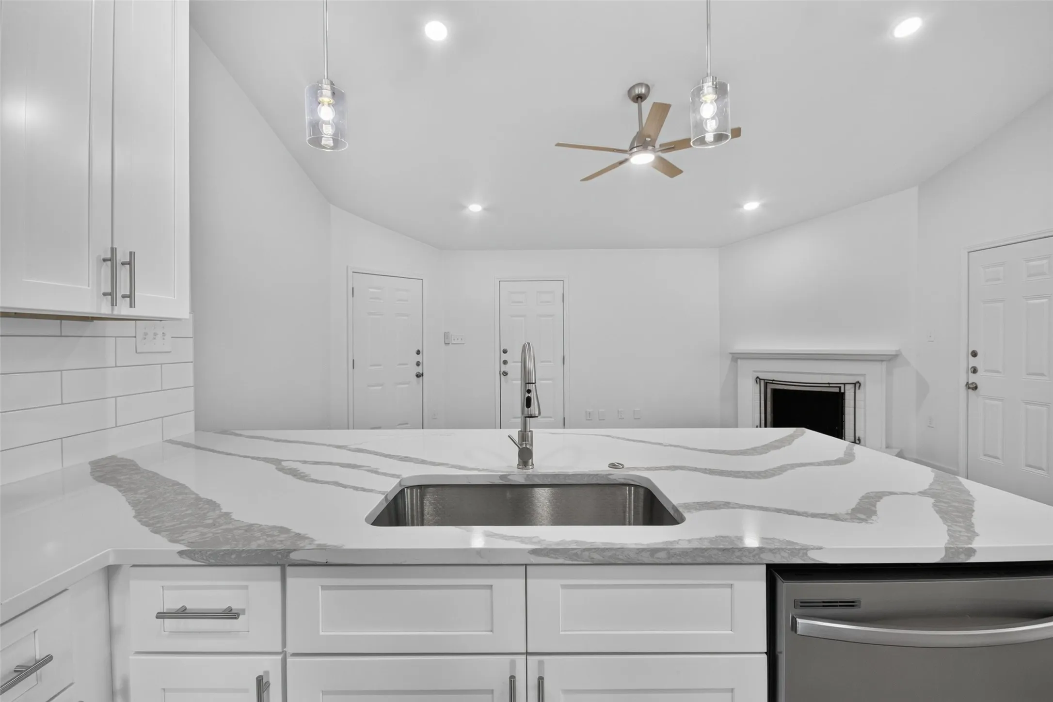 Kitchen island with an undermount sink, a gooseneck faucet, and quartz countertops with veining