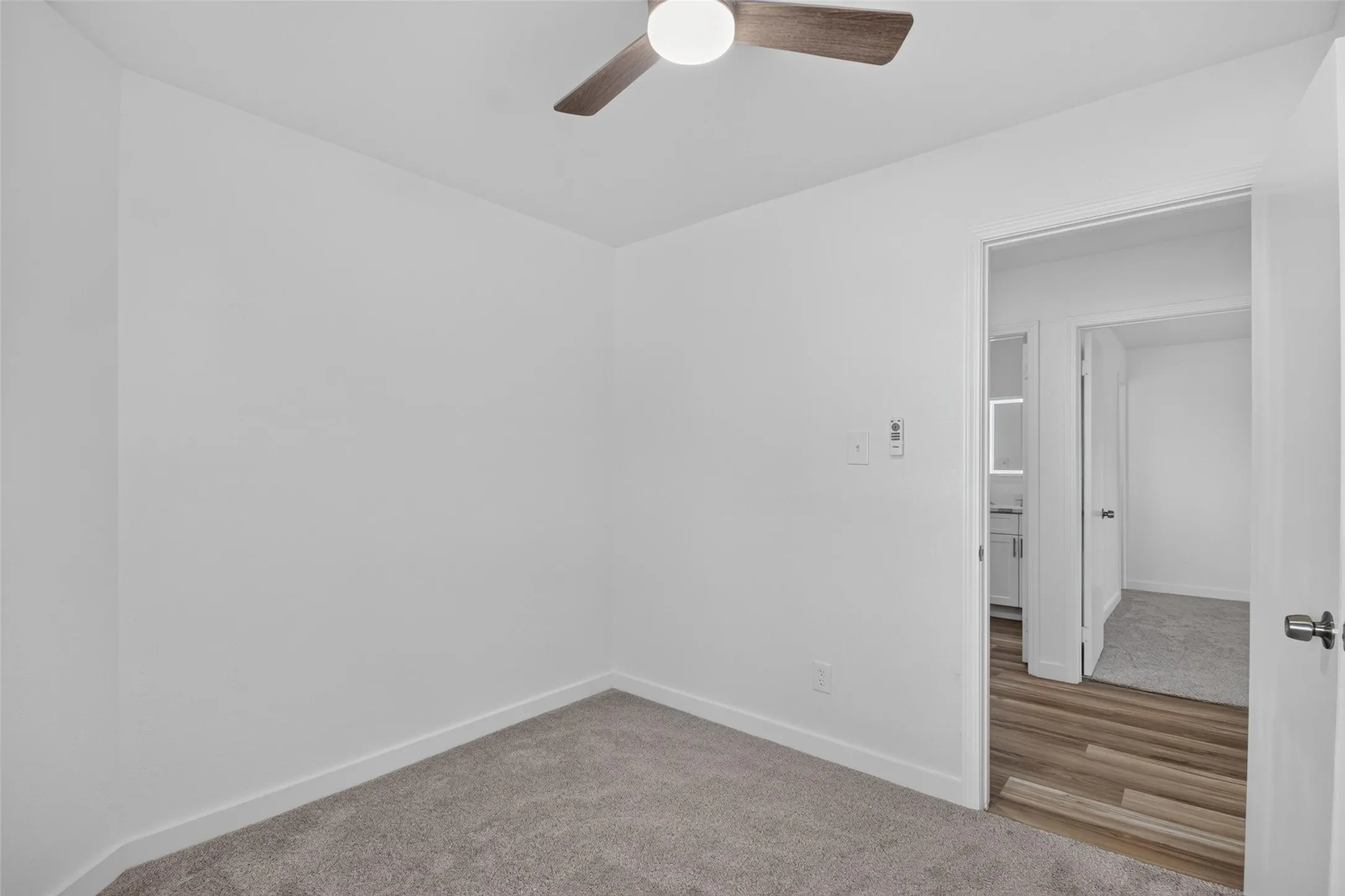 Plush carpet flooring, wood-finish flooring, ceiling fan with integrated lighting, white walls, and white trim