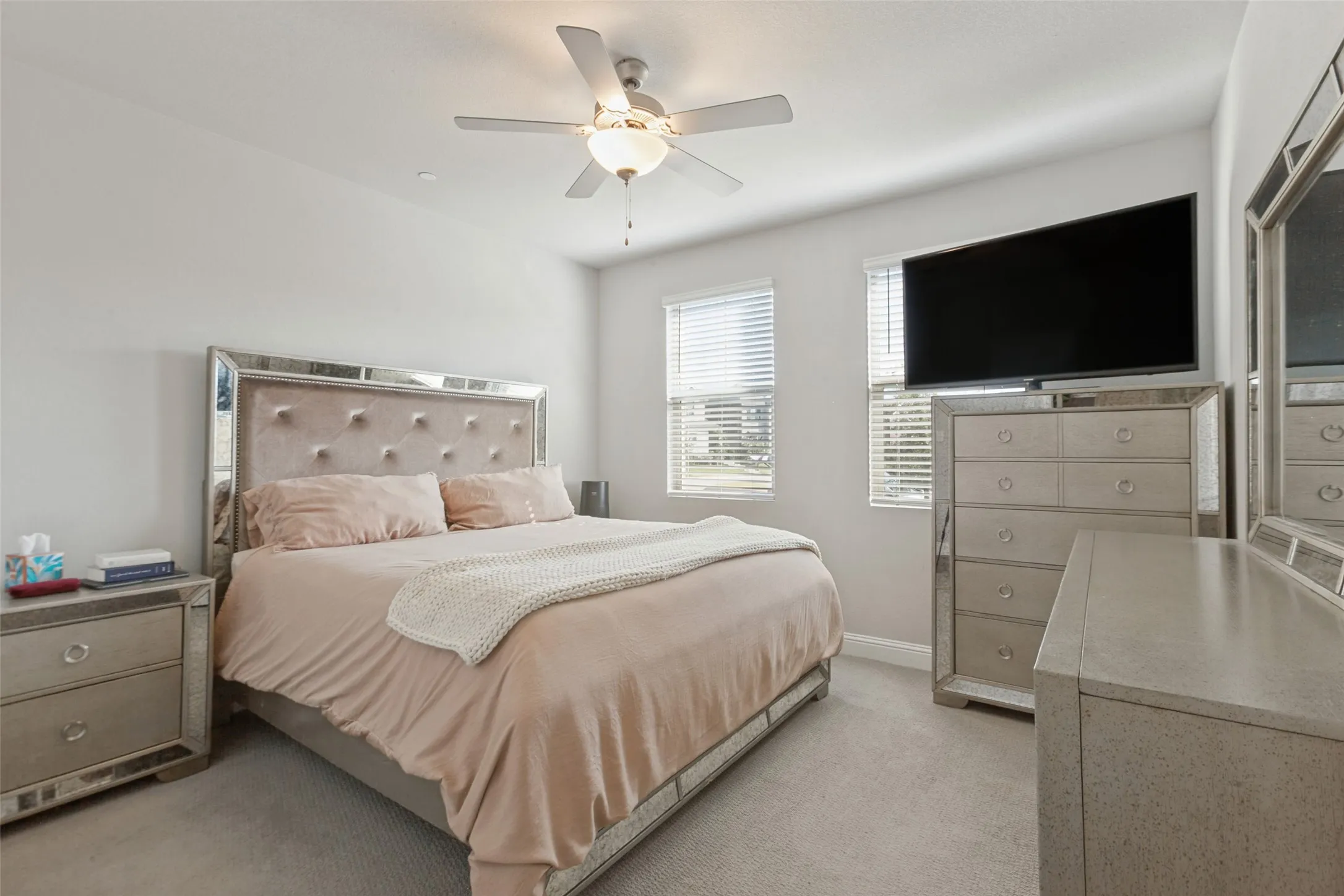 Carpeted room with a ceiling fan, two windows with blinds, and light-colored walls