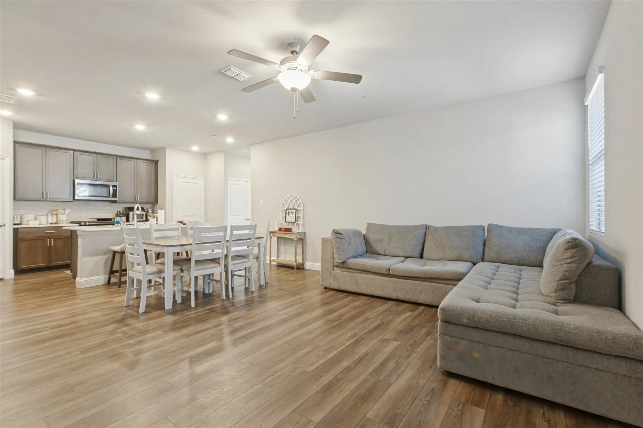 Open-concept living area featuring wood-finish flooring, recessed lighting, and a ceiling fan