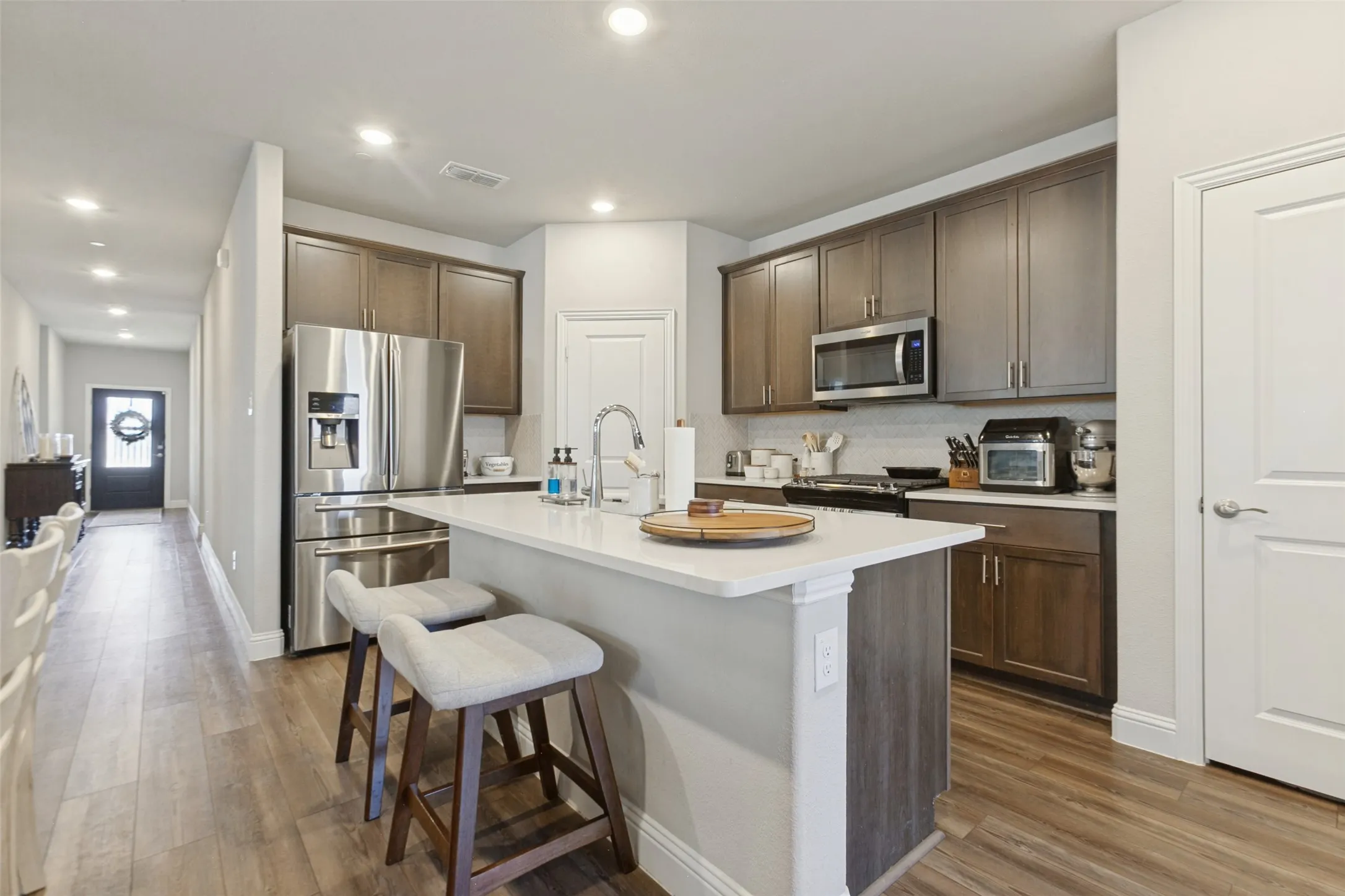 Kitchen featuring a central island with countertop seating, wood-finish flooring, recessed lighting, and stainless steel appliances