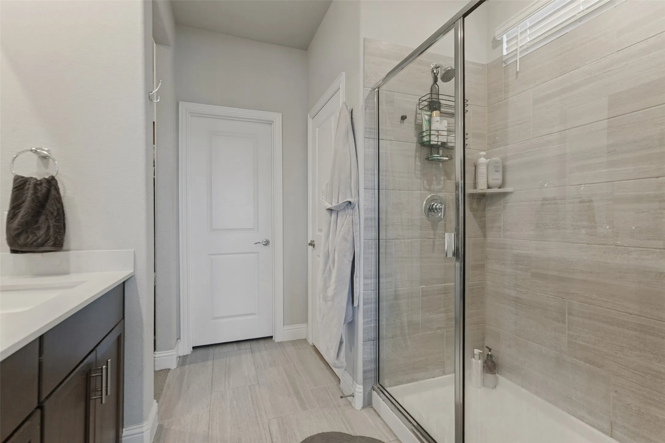 Contemporary bathroom featuring a single vanity with dark wood-finish cabinetry, a white countertop, and a built-in rectangular sink