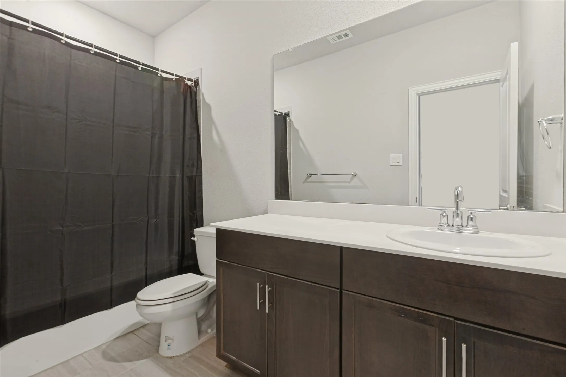 Bathroom featuring a dark wood-finish vanity with a white countertop, an integrated sink, and a large wall-mounted mirror