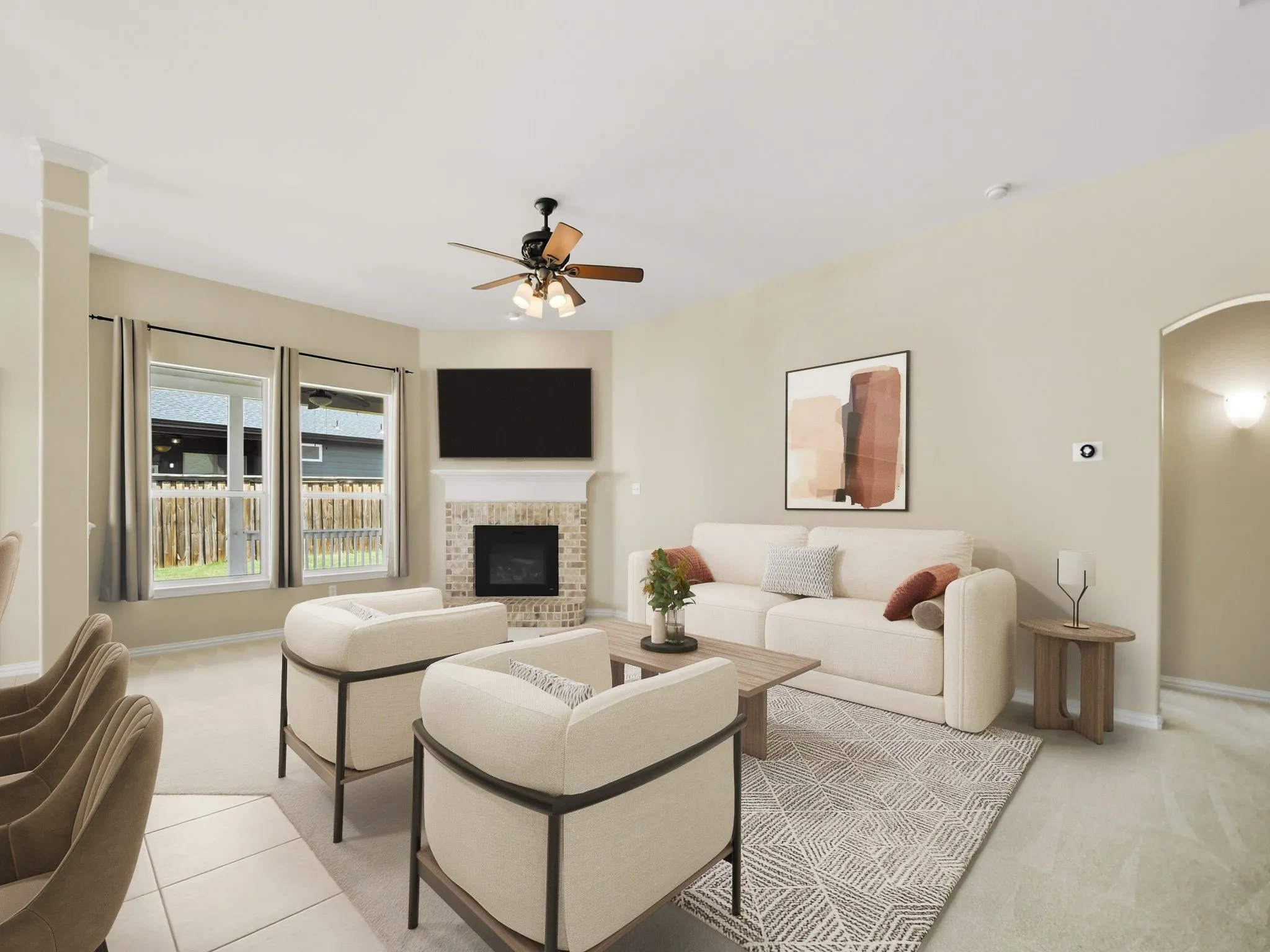 Corner fireplace with a brick surround, ceiling fan, arched doorway, and windows with backyard fencing