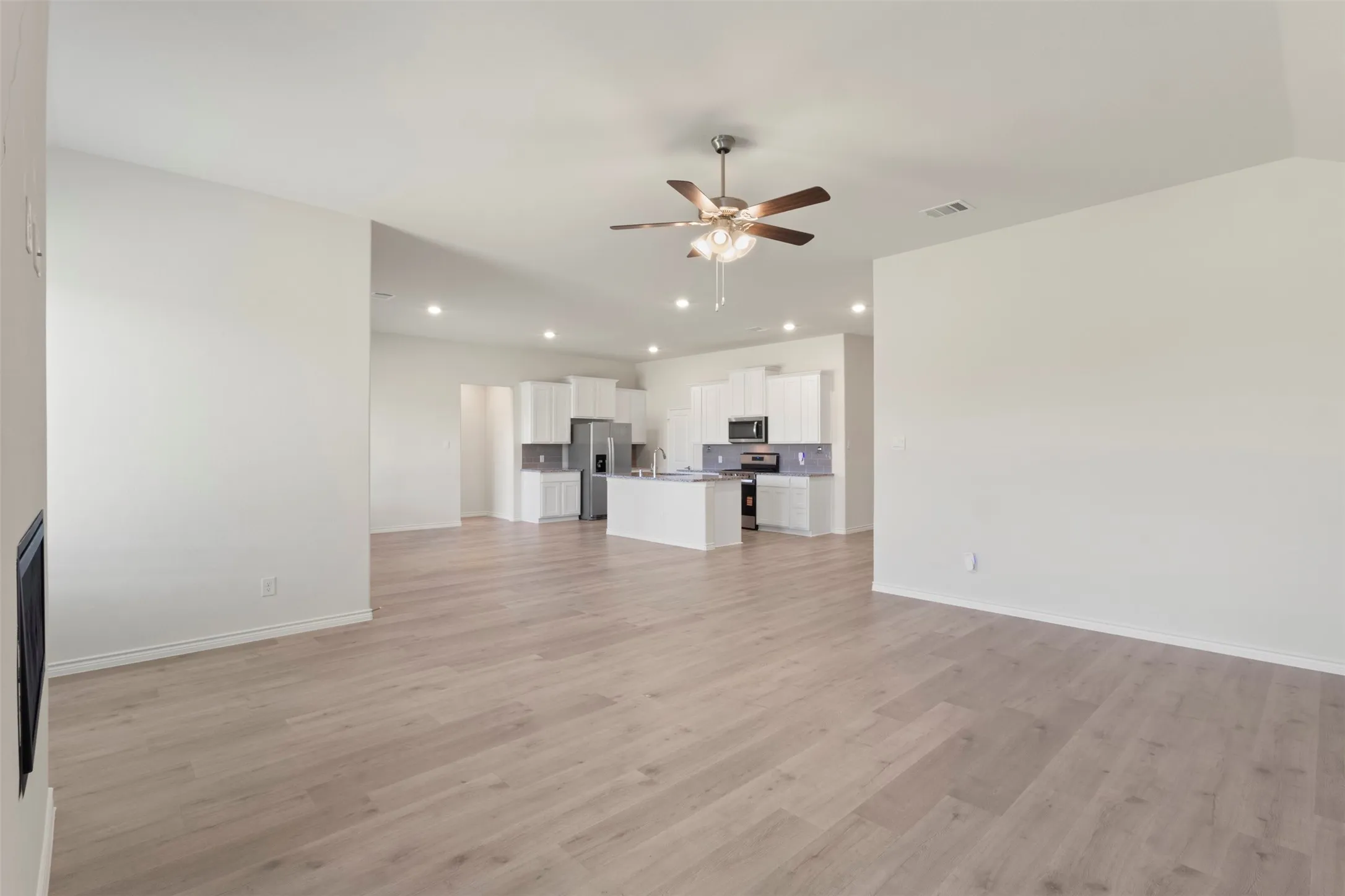 Spacious room with wood-finish flooring, recessed lighting, and a ceiling fan