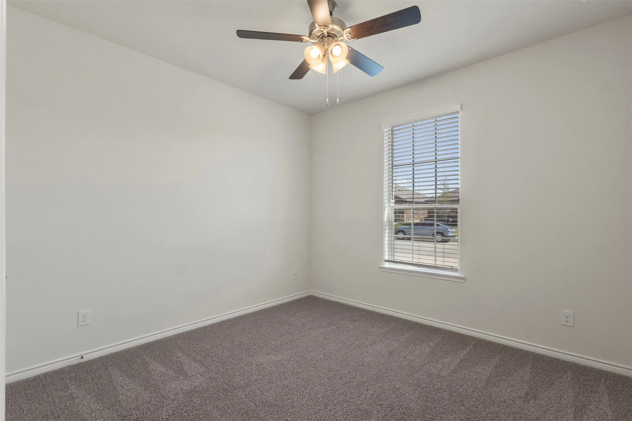 Neutral wall tones, window with horizontal blinds, ceiling fan with integrated lighting, and carpeted flooring
