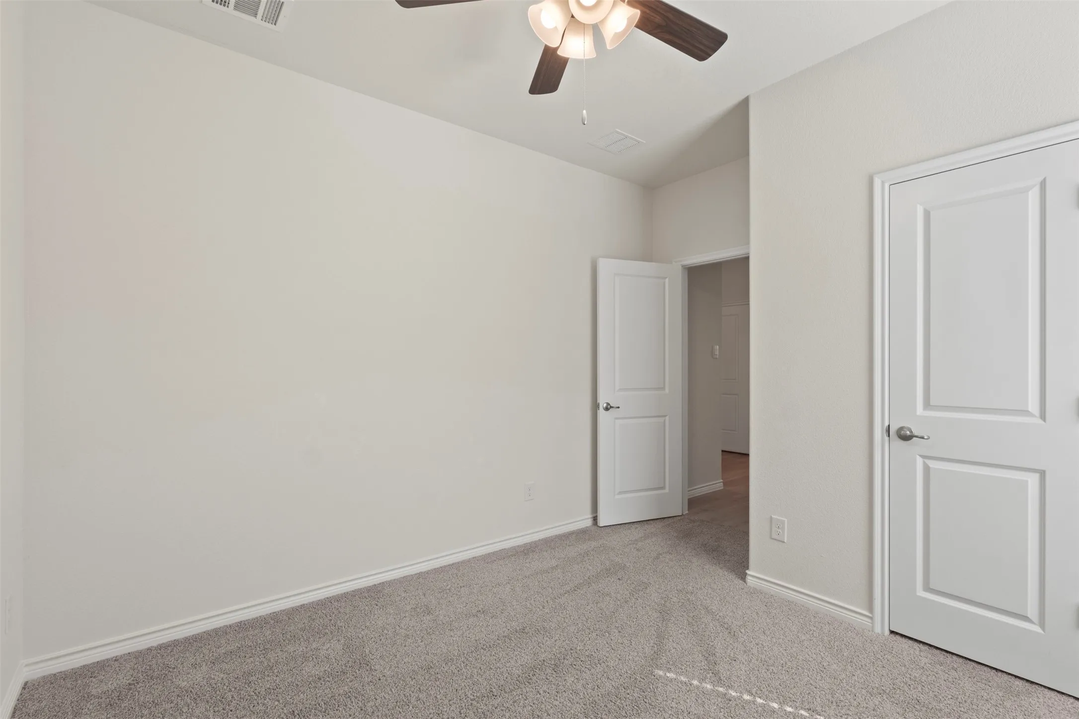 Neutral wall color, ceiling fan with light fixture, carpeted flooring, white trim, and white paneled doors