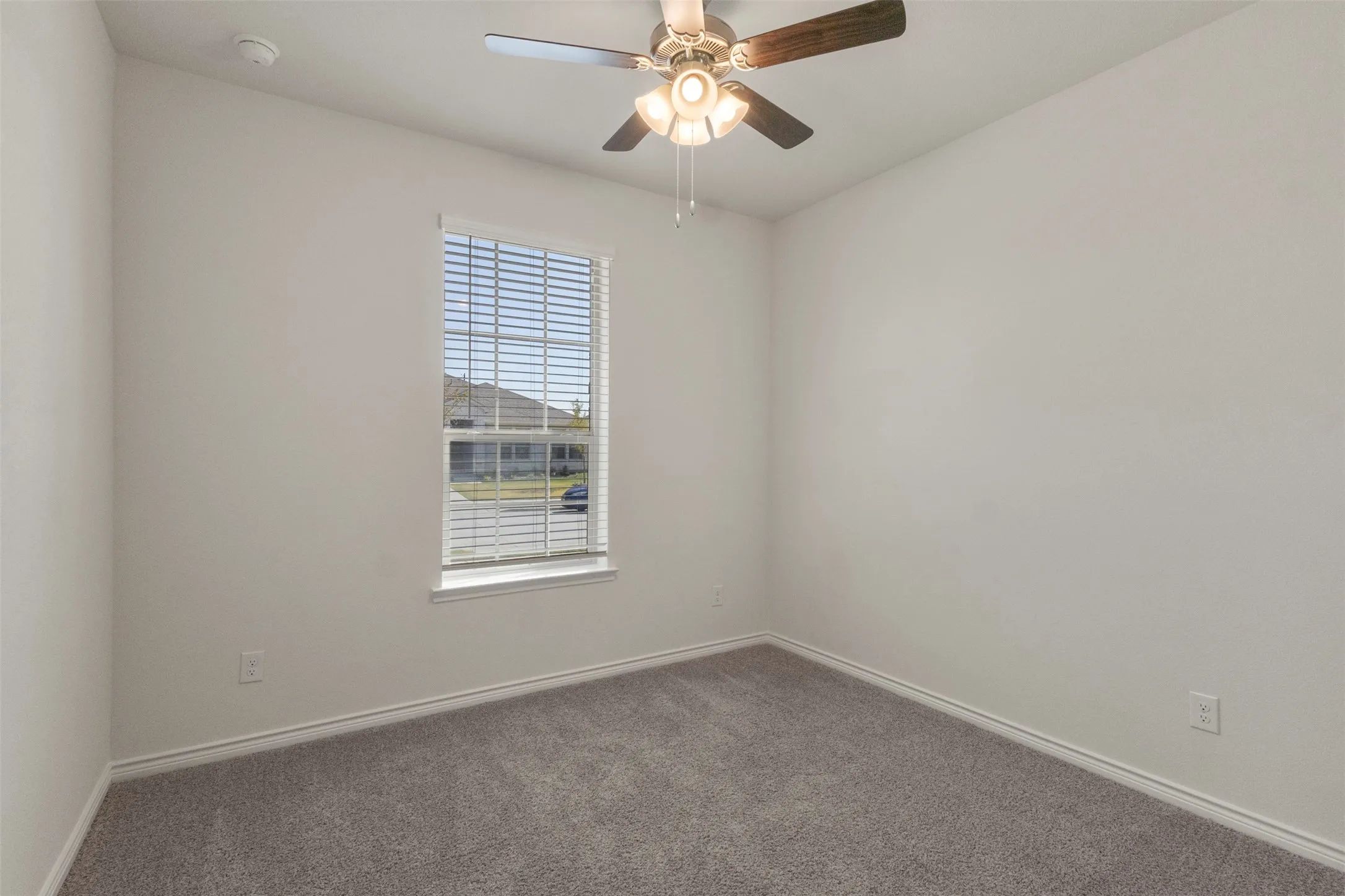 Wall-to-wall carpeting, window with blinds, ceiling fan with light fixture, and neutral wall tones