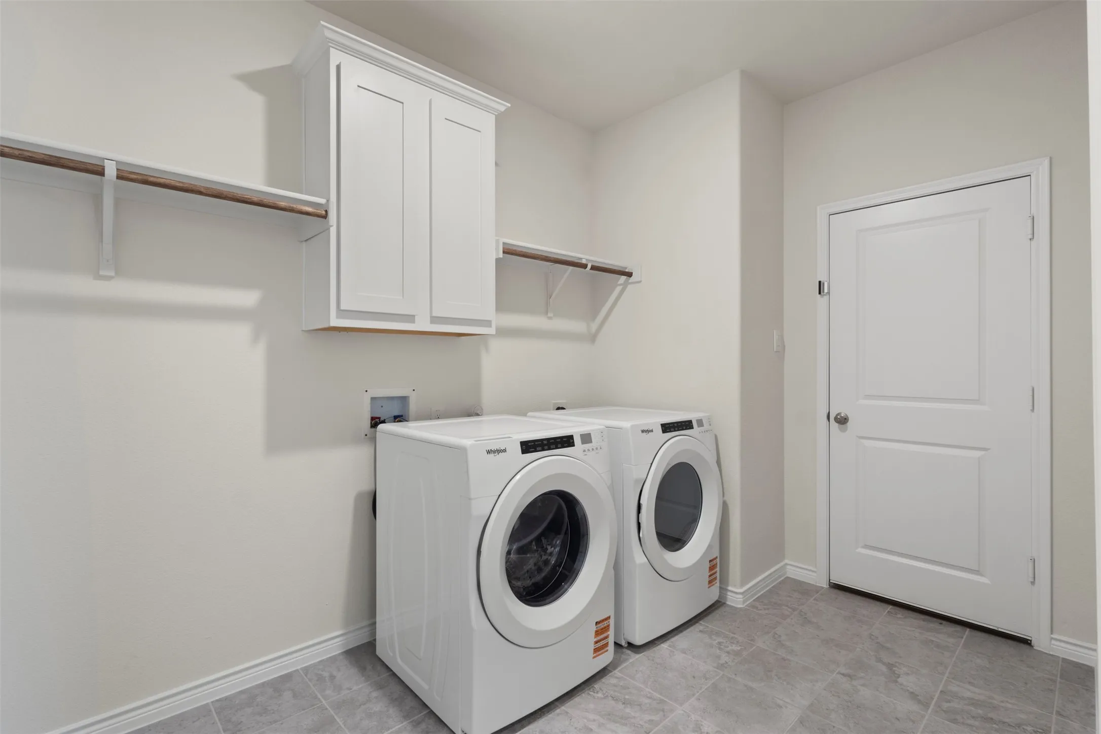White shaker-style cabinetry, a built-in hanging rod, and shelving provide storage