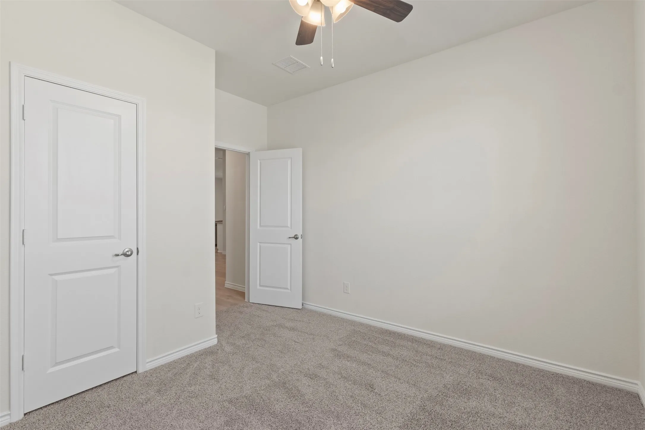 Neutral wall color with plush carpet flooring, white trim, and a ceiling fan with integrated lighting