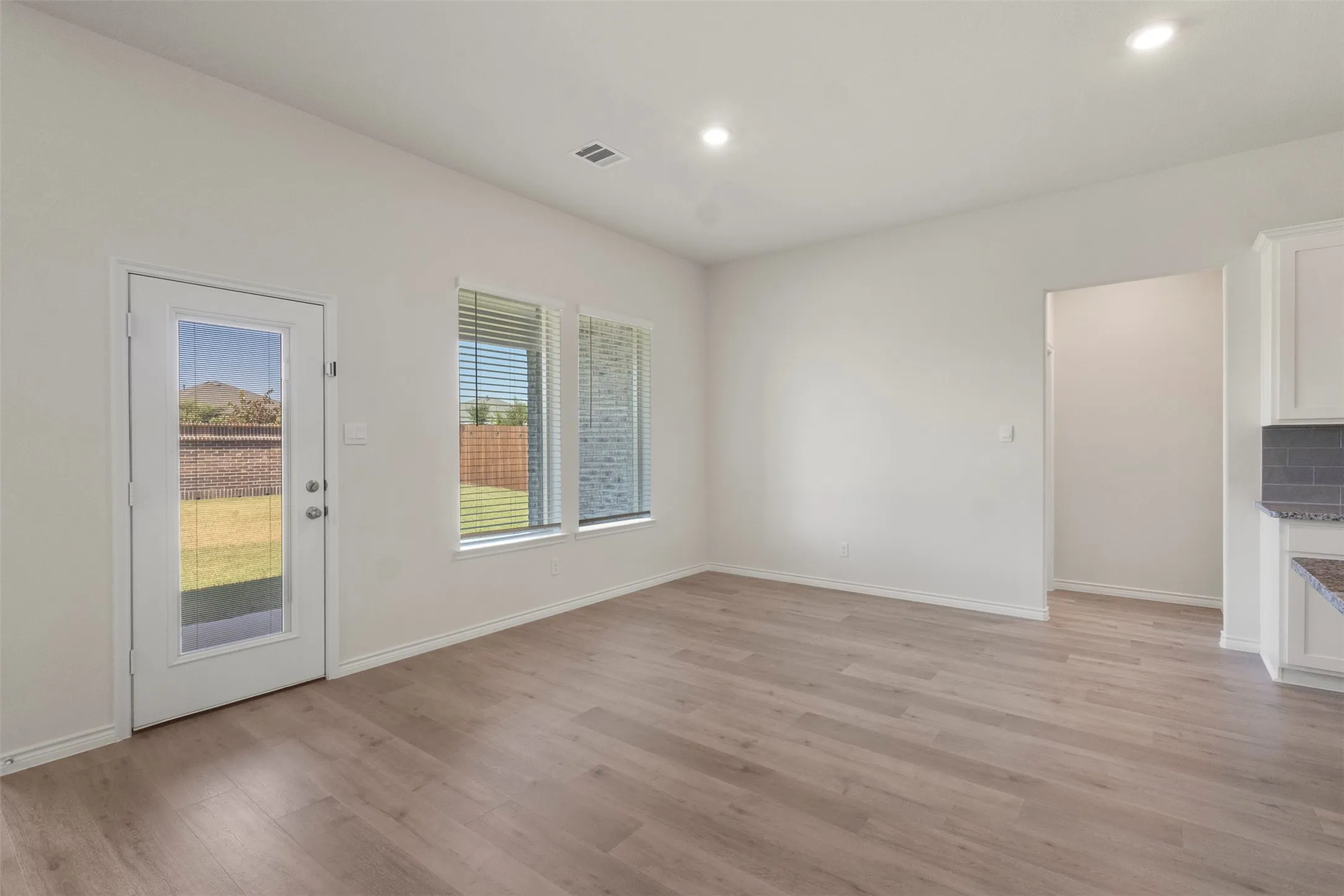 Wood-finish flooring, recessed lighting, and white walls with a matte finish
