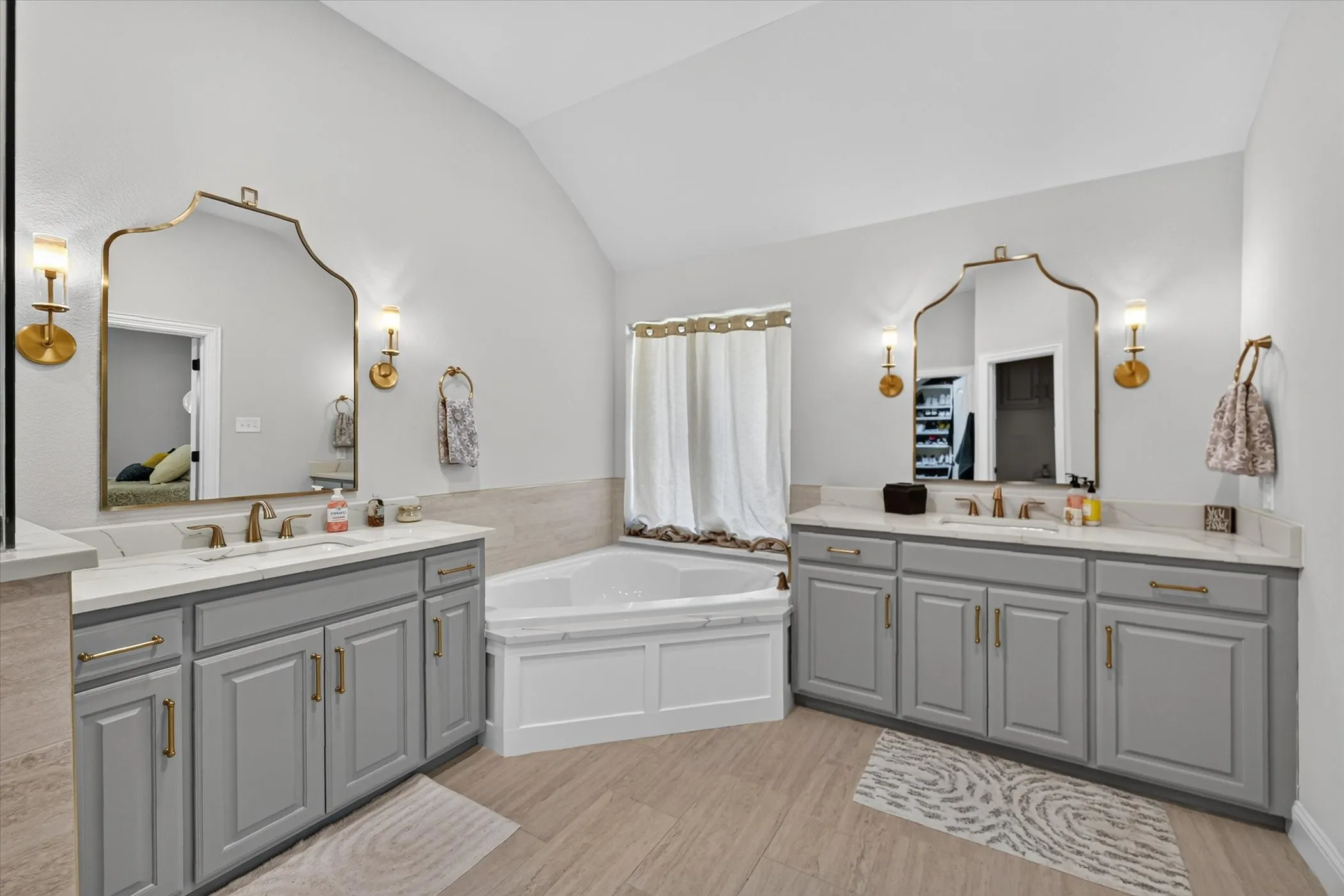 Dual vanities with quartz countertops, custom gray cabinetry, and brass hardware