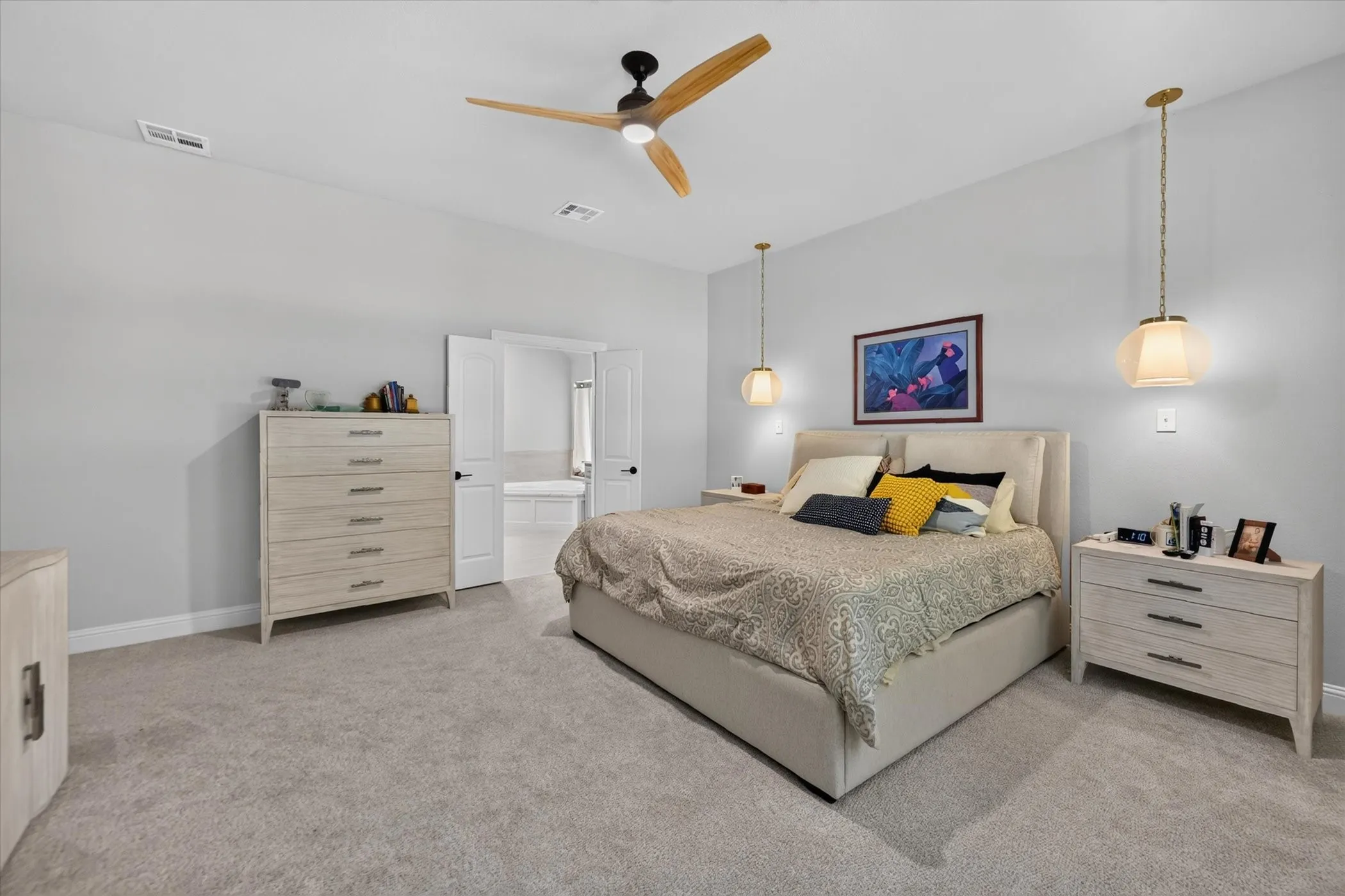 Spacious room featuring light gray carpeting, neutral wall color, a contemporary ceiling fan, and two pendant light fixtures