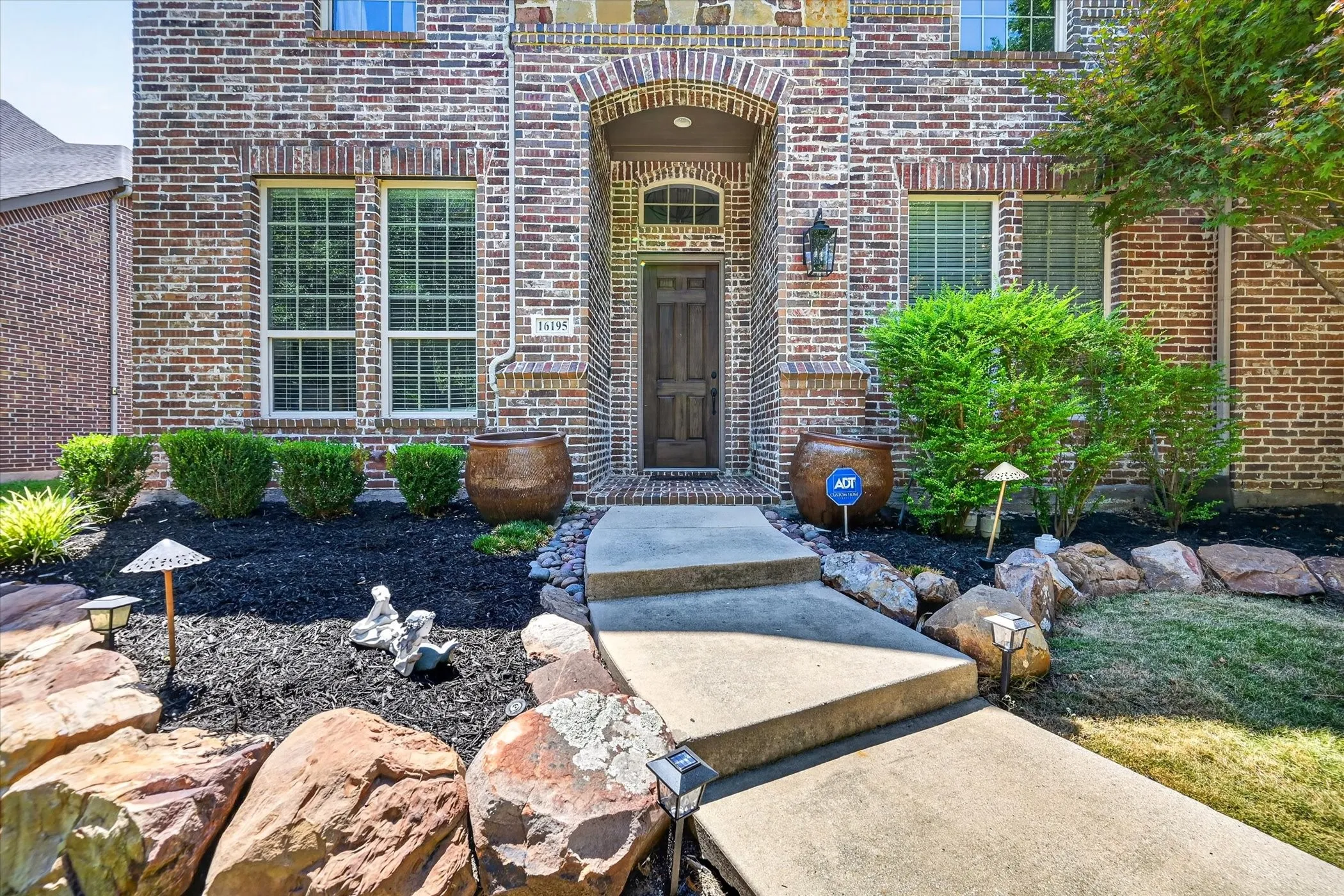 Brick facade with stone accents, arched entryway, and a solid wood front door