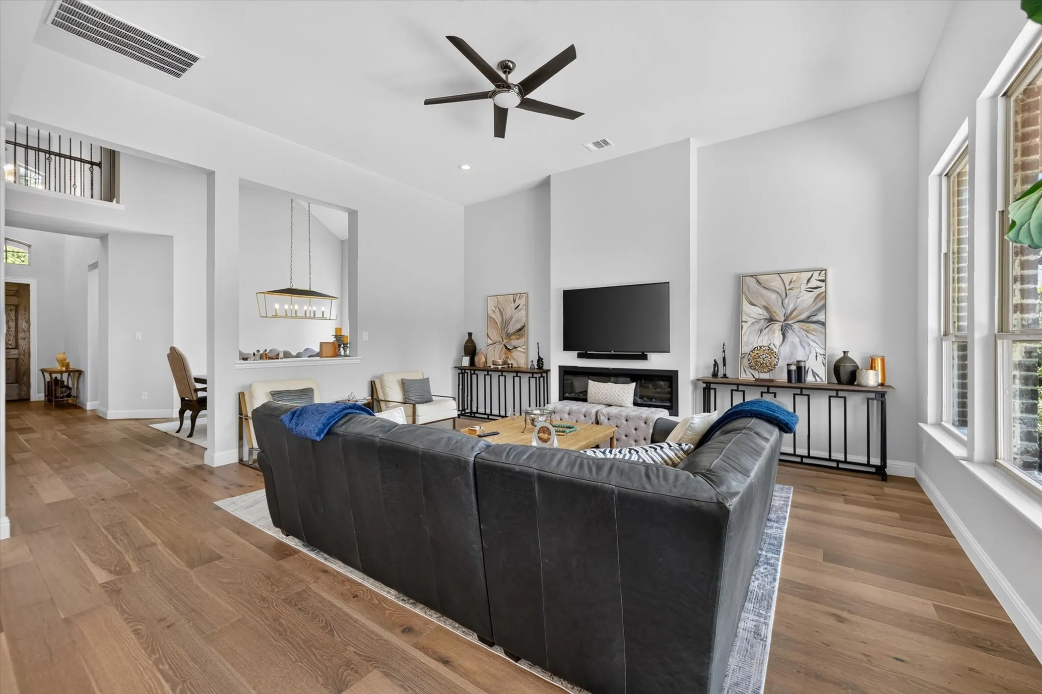 High ceilings, wood-finish flooring, contemporary fireplace, recessed lighting, and large windows