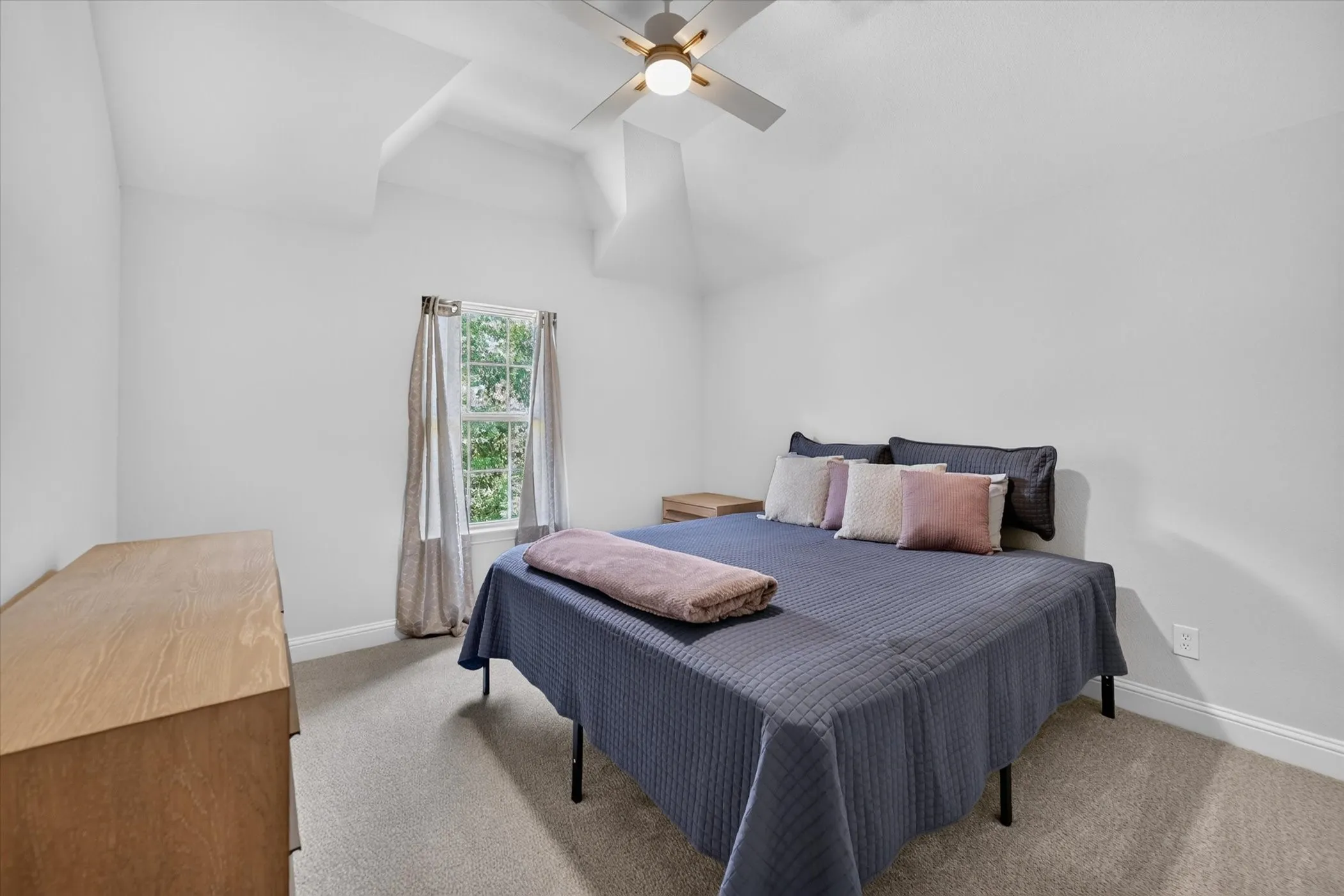 Vaulted ceiling with a ceiling fan, window with curtains, and carpeting