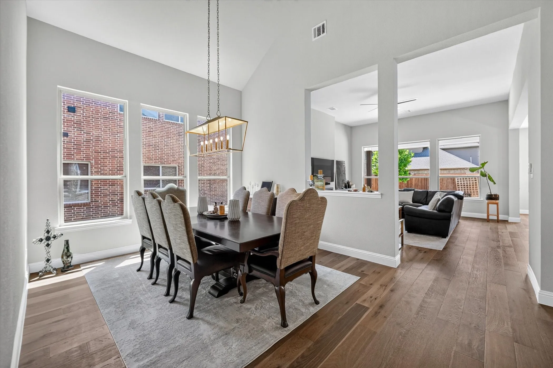 Dining area with vaulted ceilings, wood-finish flooring, a contemporary chandelier, and multiple windows