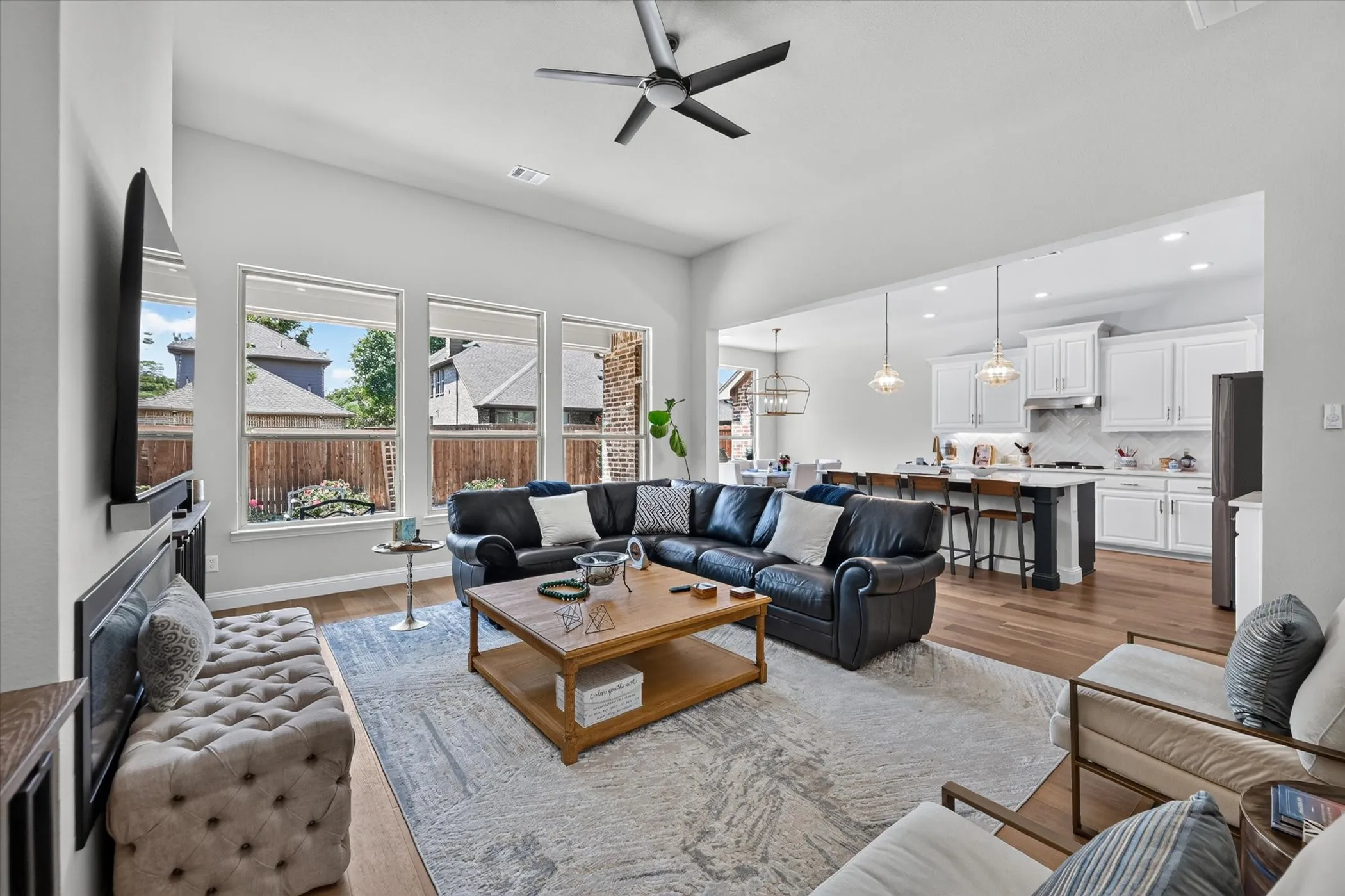 Open-concept living area with high ceilings, wood-finish flooring, and multiple windows
