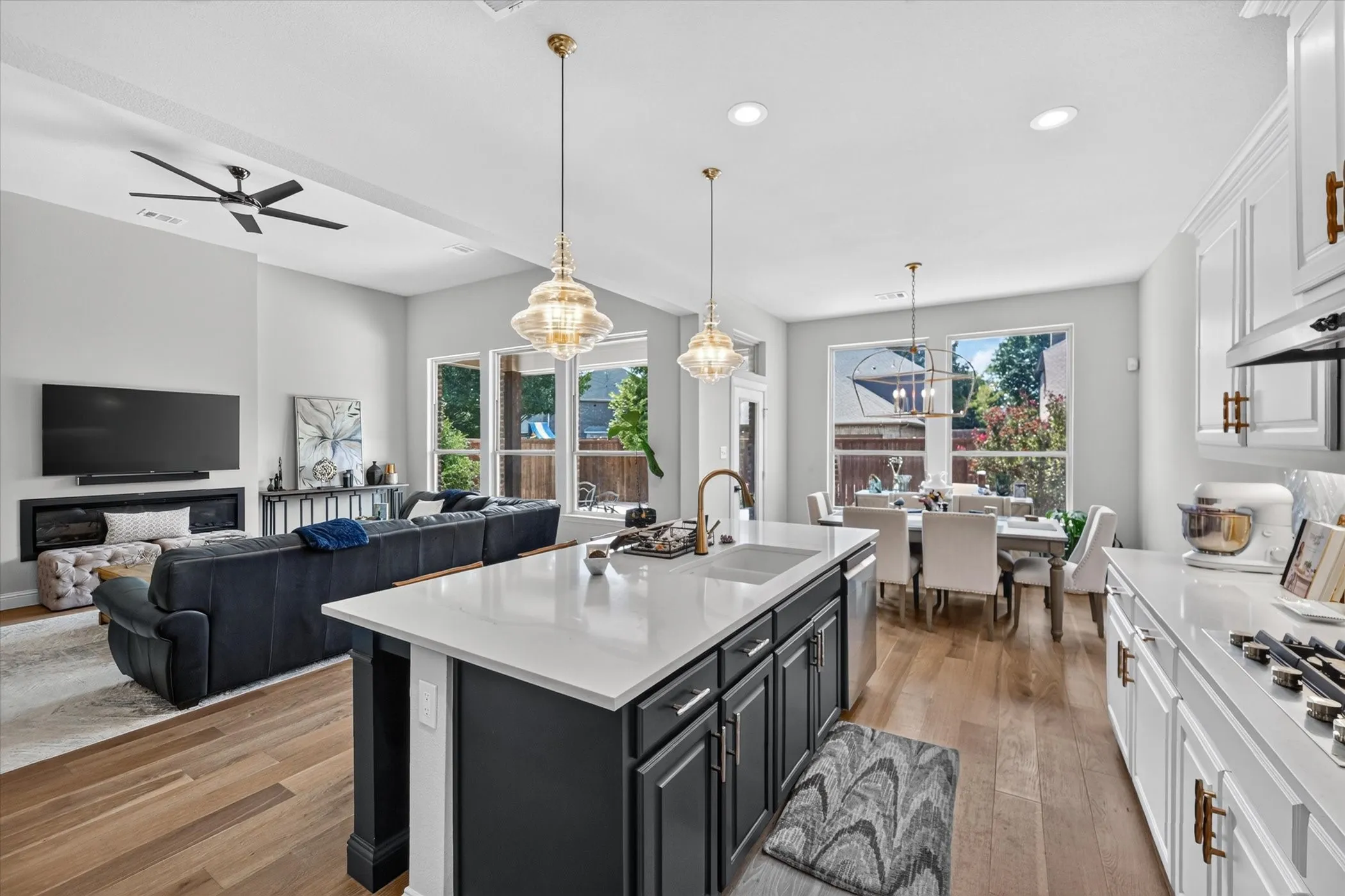 Open-concept living space featuring wood-finish flooring, a large kitchen island with a built-in sink, and a dining area with ample natural light