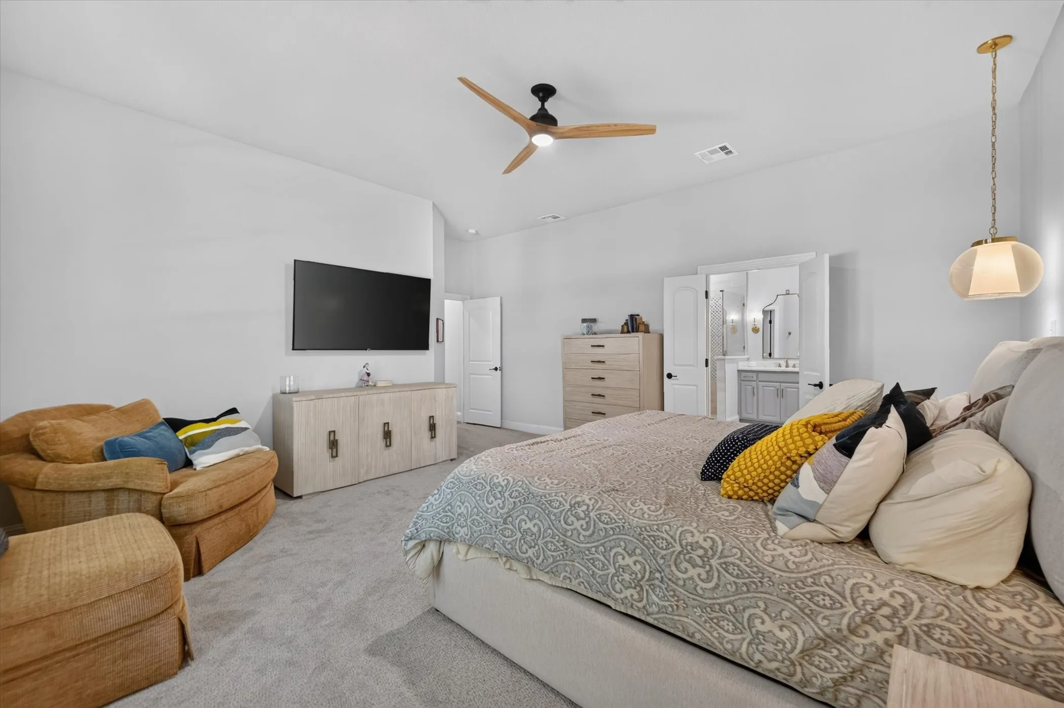 Vaulted ceiling with a wood-finish ceiling fan, wall-mounted television, and light gray carpeting