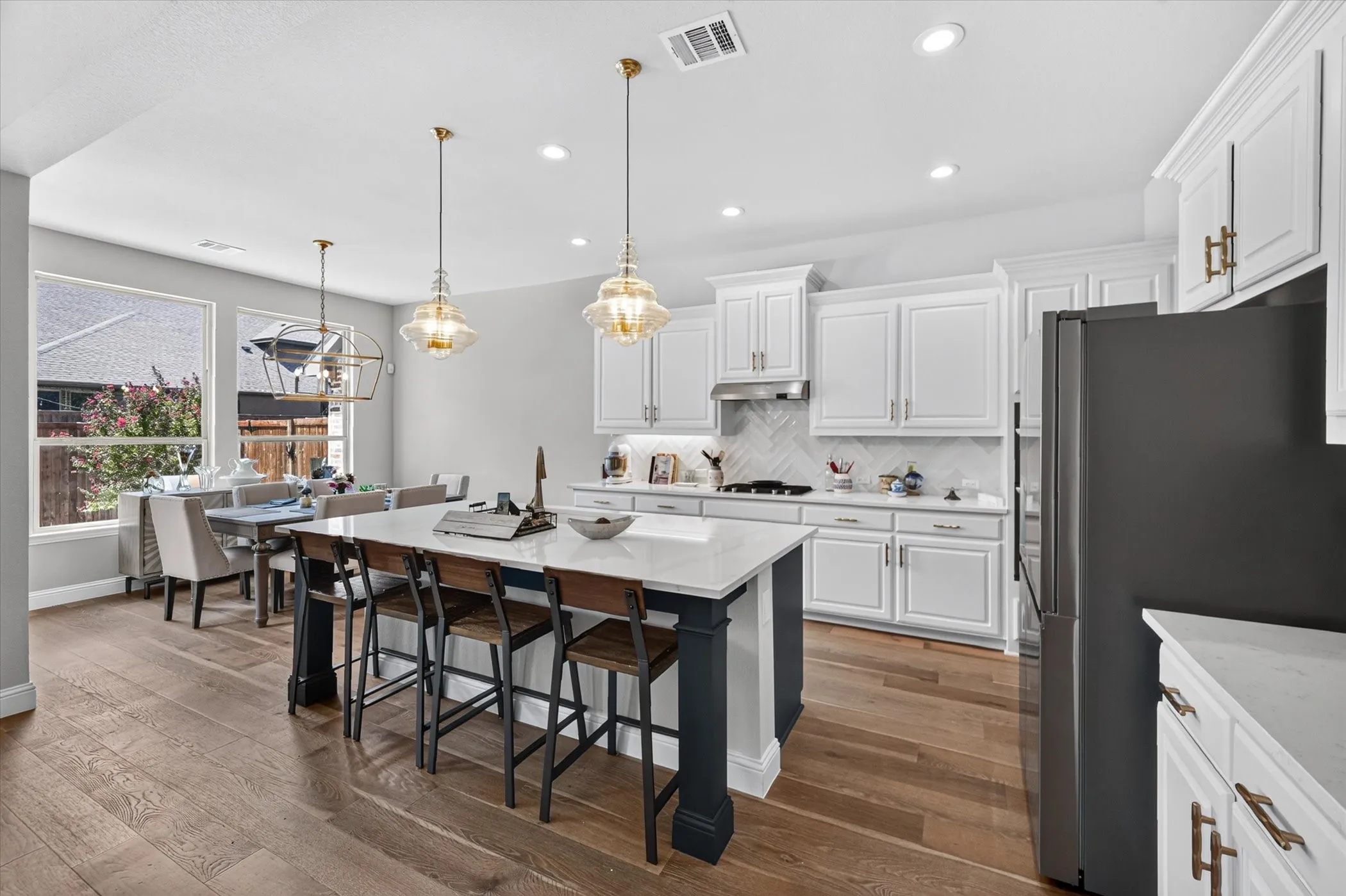 Open-concept kitchen featuring an island with counter seating, shaker-style cabinetry, wood-finish flooring, and pendant lighting